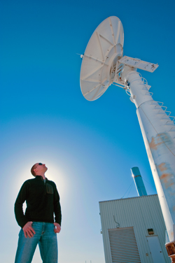 Brian Post stands under an antenna at the ground station at Sandia National Labs during the MTI satellite’s 55,000th orbit (photo by Randy Montoya).