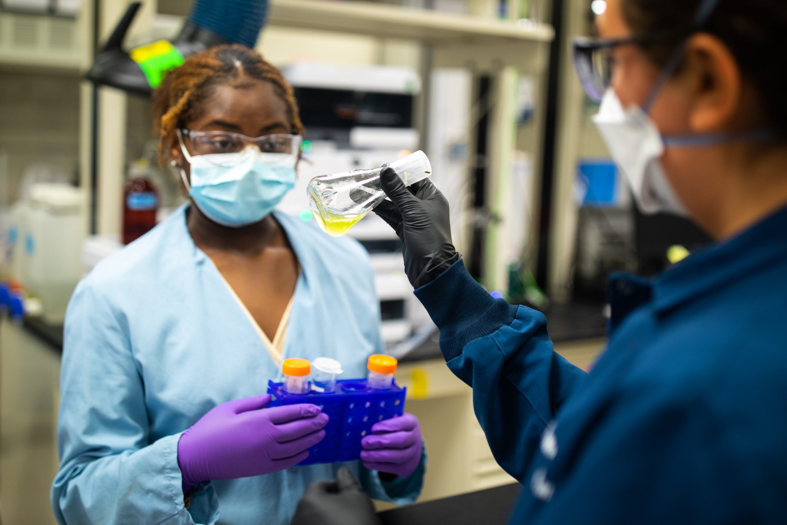 Brook Davis, a molecular and microbiology summer intern from University of Arkansas at Pine Bluff, with the aid of Morgan Mackenzie, right, is preparing algae samples for a microbiome investigation at Sandia National Laboratories. Photo By Craig Fritz. Click on the thumbnail for a high-resolution image.