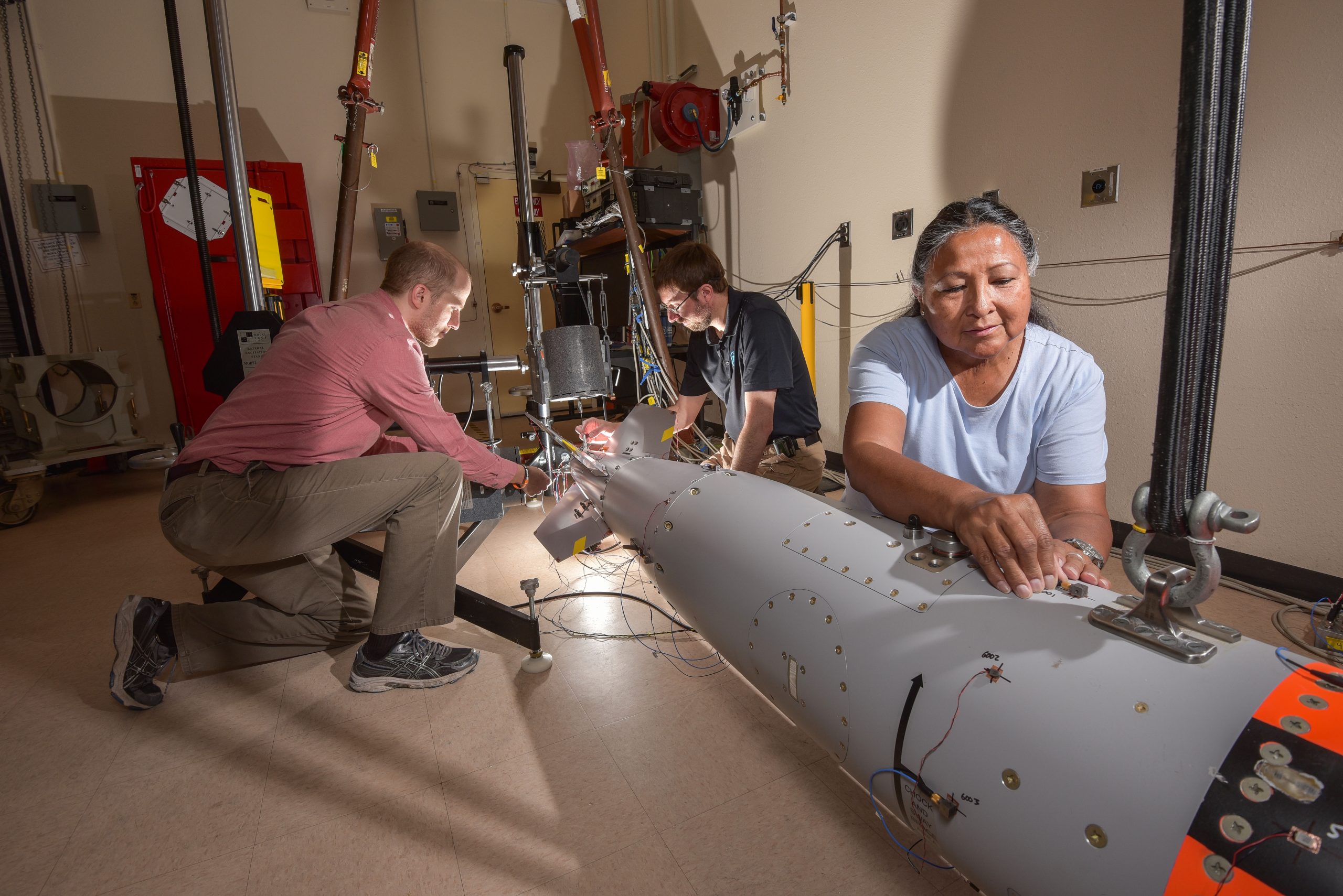 A B61-12 model goes through a vibration test to analyze structural integrity. Placing the diagnostics are Sandia National Laboratories’ Daniel Rohe, left, Patrick Hunter, center, and Maxine Norton before the COVID-19 pandemic.