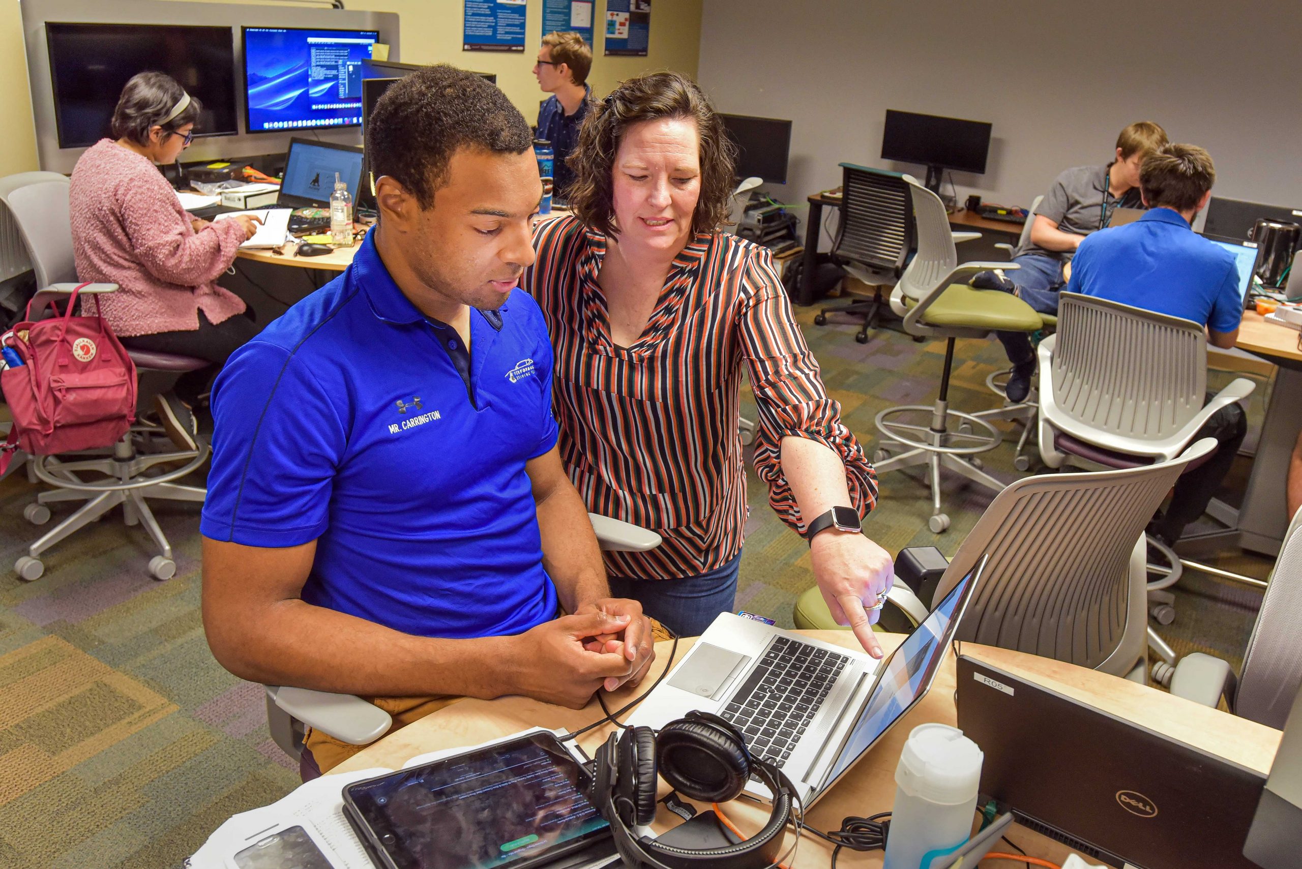 Sandia National Laboratories CECOR coordinator Tommie Kuykendall, center, assists an intern working in cybersecurity research and training.