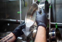 Sandia National Laboratories technologist Levi Van Bastian fills a hopper with raw material to print on the Laser Engineered Net Shaping machine. What appears to be a liquid is powdered metal.