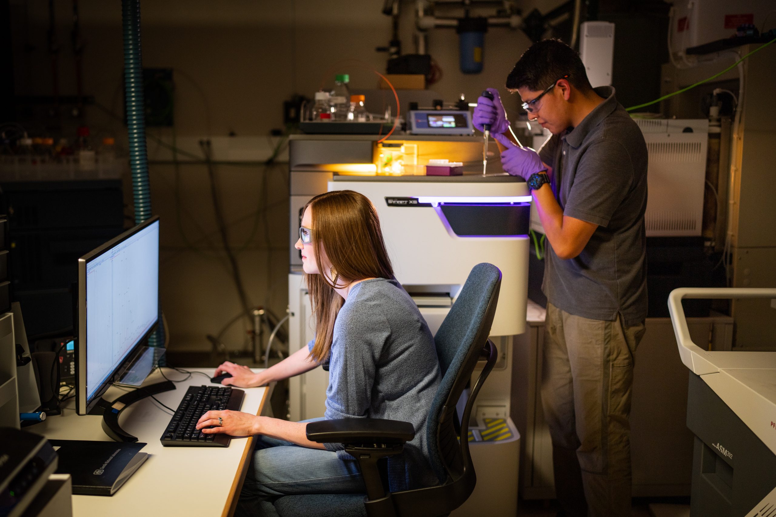 Jessica Kustas, left, and Andre Benally work with a mass spectrometer at Sandia National Laboratories while trying to pair up technologies to go beyond just absorbing PFAS.