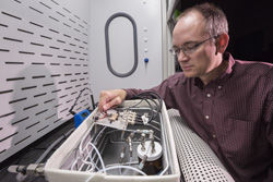 Sandia National Laboratories researcher Chris Brotherton checks tiny sensors in a test fixture, where he exposes them to different environments and measures their response to see how they perform. Brotherton is principal investigator on a project aimed at detecting a common type of homemade explosive made with hydrogen peroxide.