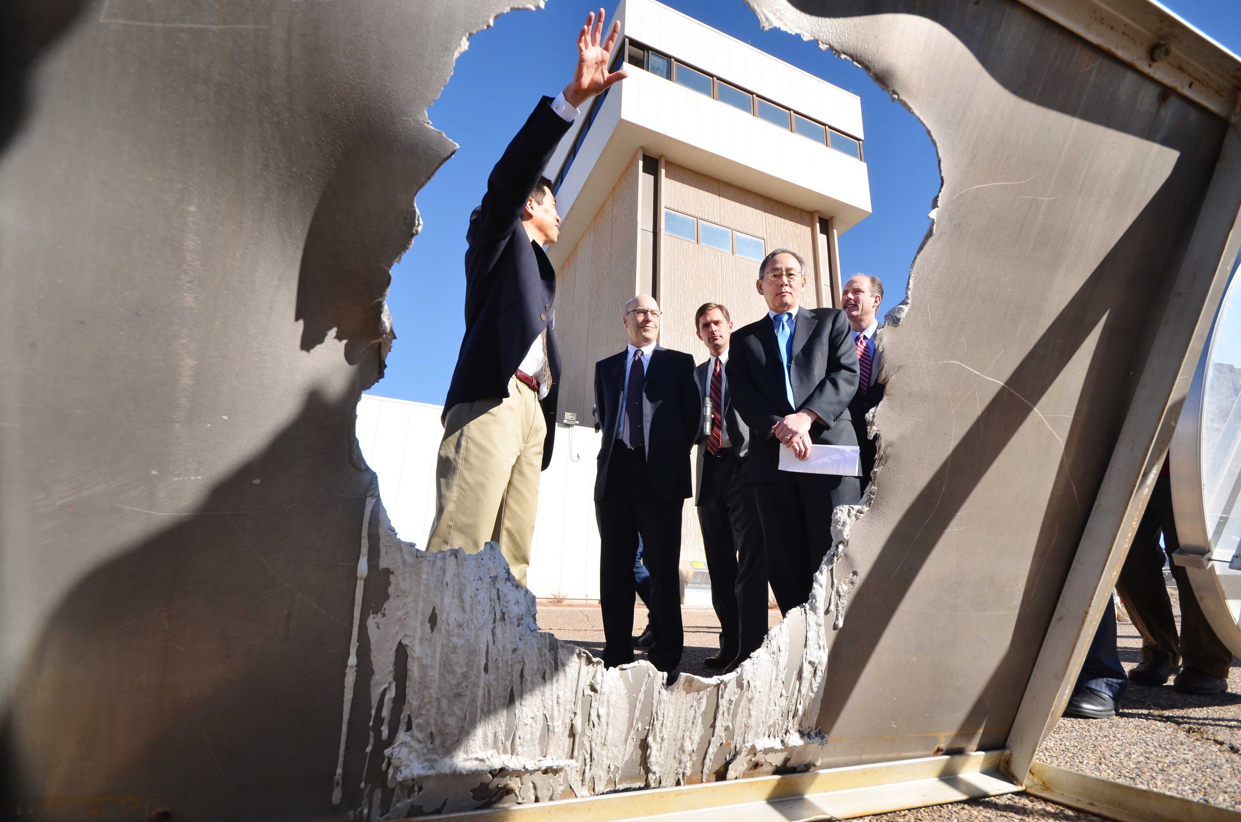 Sandia National Laboratories researcher Cliff Ho, left, shows Secretary of Energy Steven Chu, second from right, a half-inch thick sheet of aluminum that was melted in 23 seconds by a beam of concentrated sunlight from 105 heliostats at the National Solar Thermal Test Facility during a visit on Jan. 26, 2012.