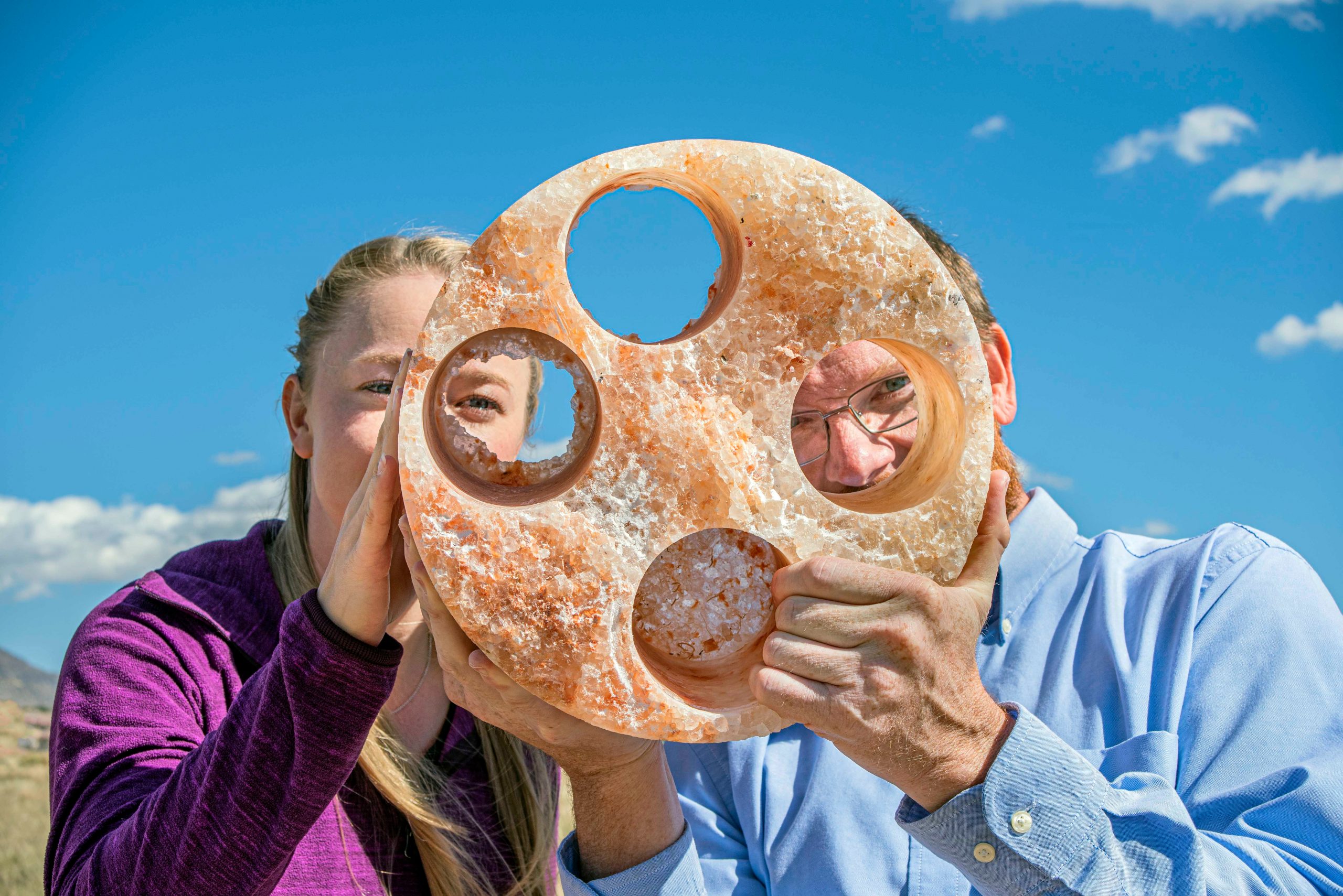 Sandia National Laboratories researchers Melissa Mills, left, and Kristopher Kuhlman peer through a salt sample from their Waste Isolation Pilot Plant experimental site.