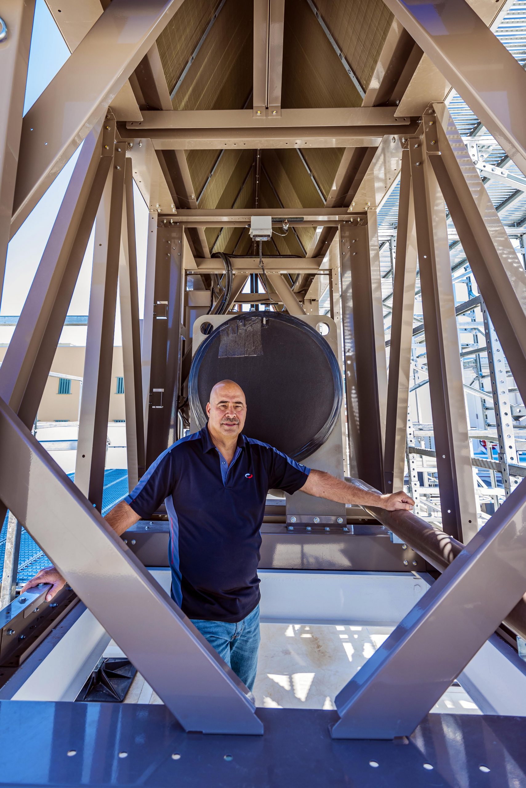 Sandia National Laboratories engineering lead David J. Martinez stands inside the first thermosyphon cooler installed on the roof of Sandia's supercomputer center.