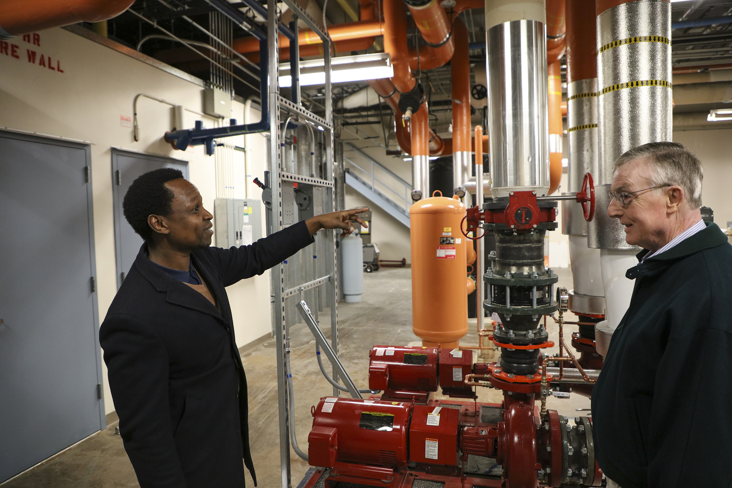 nStone Project Manager Munene Kasina, left, and nStone President Donald Lincoln discuss a new hot water pump the company helped install at Sandia National Laboratories.
