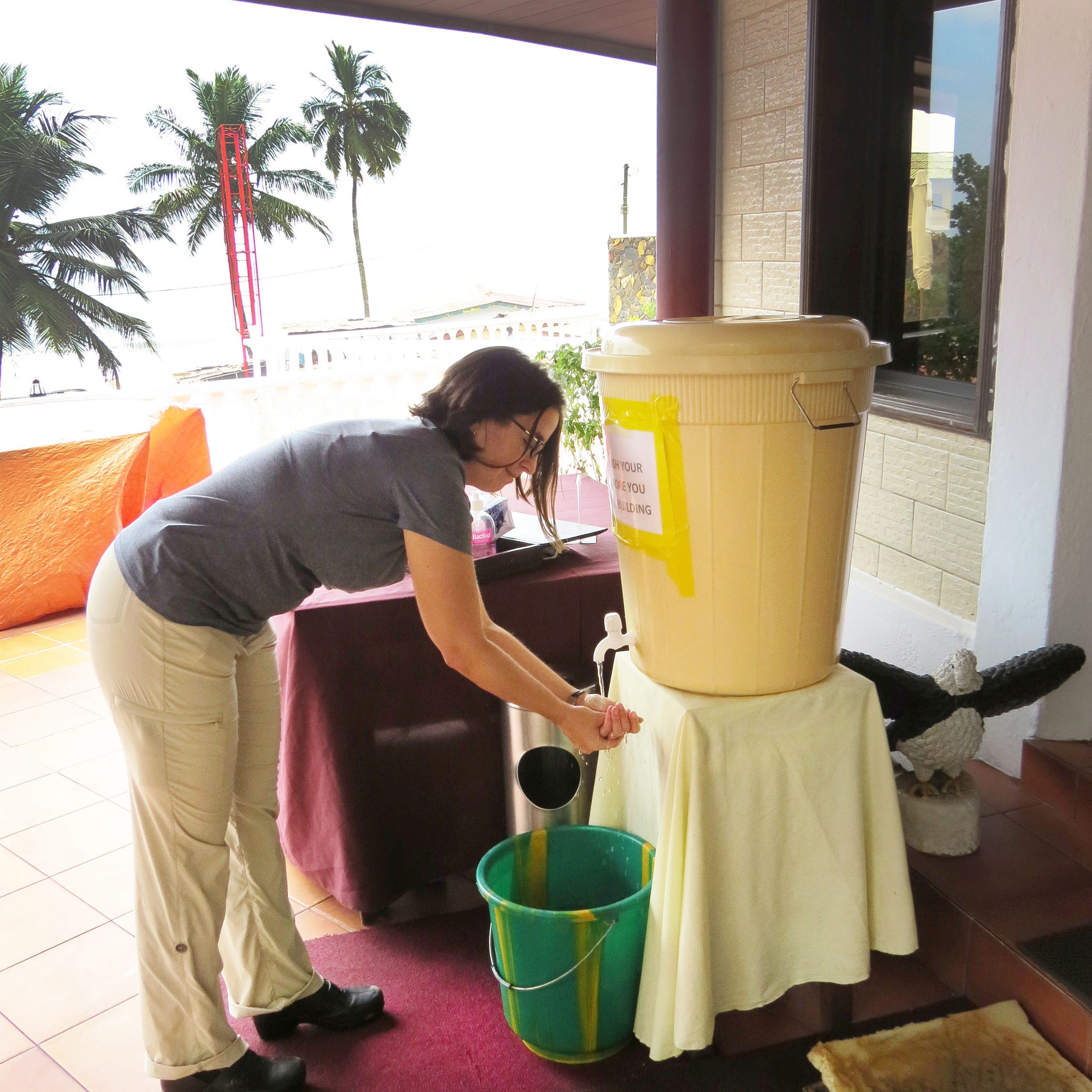 Jen Gaudioso, senior manager of the International Biological and Chemical Threat Reduction program, washes her hands in bleach before entering a hotel for meetings with U.S. aid organizations in Liberia.