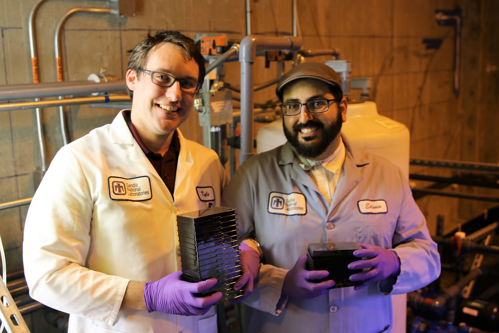 Sandia National Laboratories inhibitor search team scientists Kyle Seamon, left, and Edwin Saada hold stacks of 384-well plates used to search for small-molecule Cas9 inhibitors.