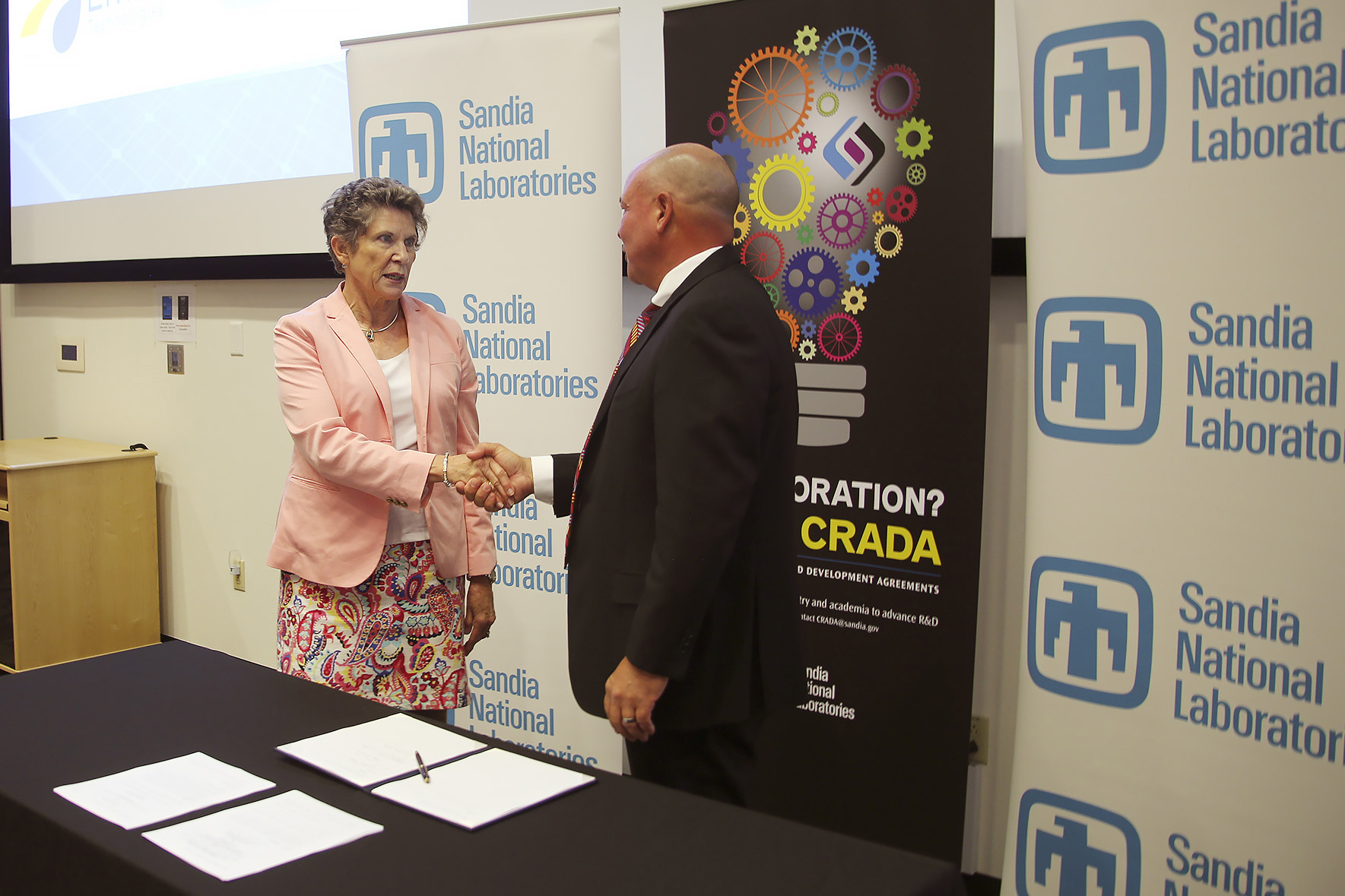 Sandia National Laboratories associate labs director Dori Ellis shakes hands with Emera Technologies CEO Rob Bennett following the signing of a Cooperative Research and Development Agreement between the laboratories and the utility company.