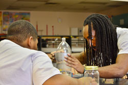 HMTech instructor Tyler Garrett, a component and tester surety engineer at Sandia National Laboratories, helps a student prepare an experiment.