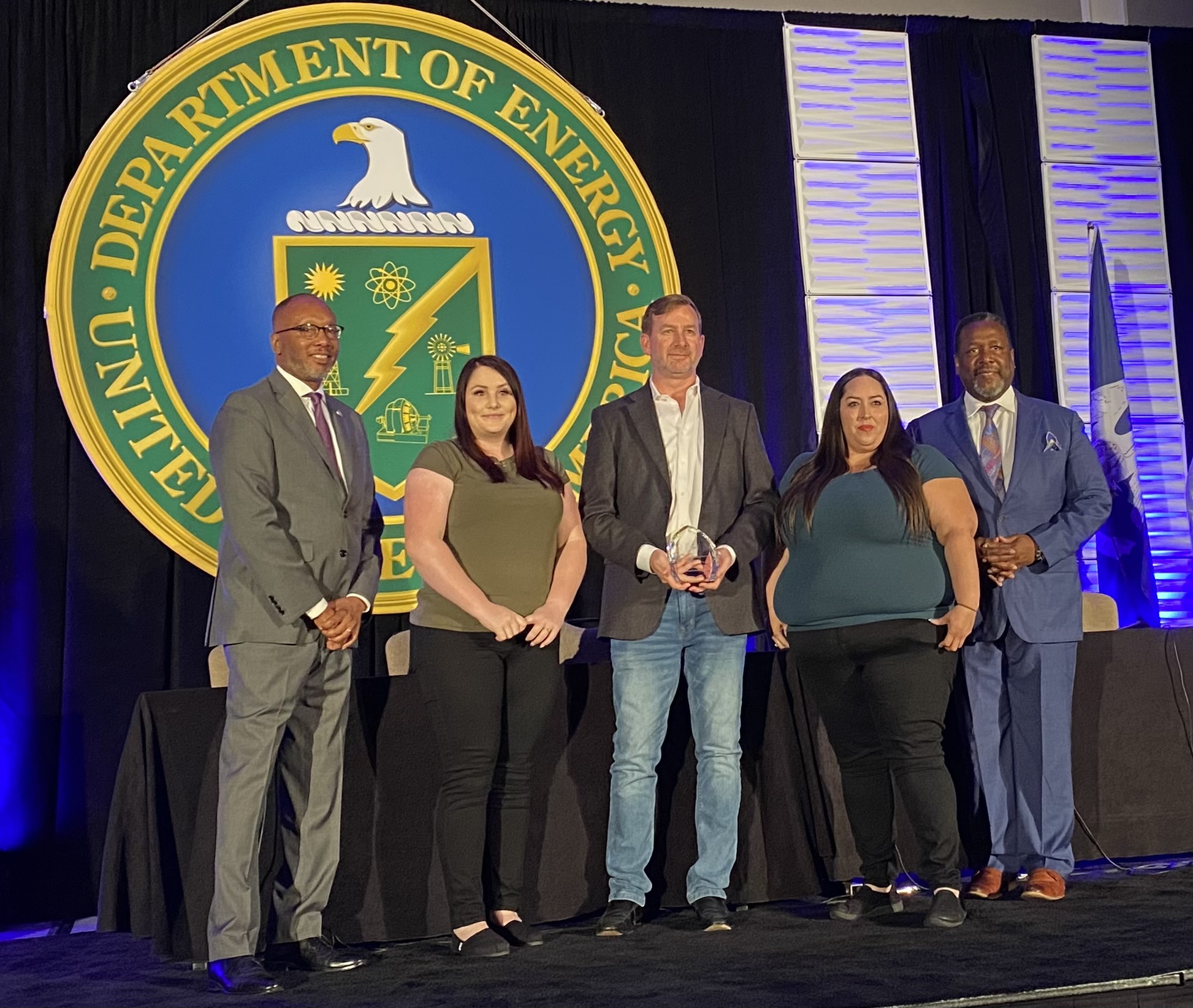 The team from Wildflower International receives its award from DOE for HUBZone Small Business of the Year, recognizing its critical support of Sandia, Los Alamos and Lawrence Livermore national labs. Cheri Chandler, operations manager, second from left, Justin Thigpen, DOE business unit director, Marlena Lucero, senior manager.