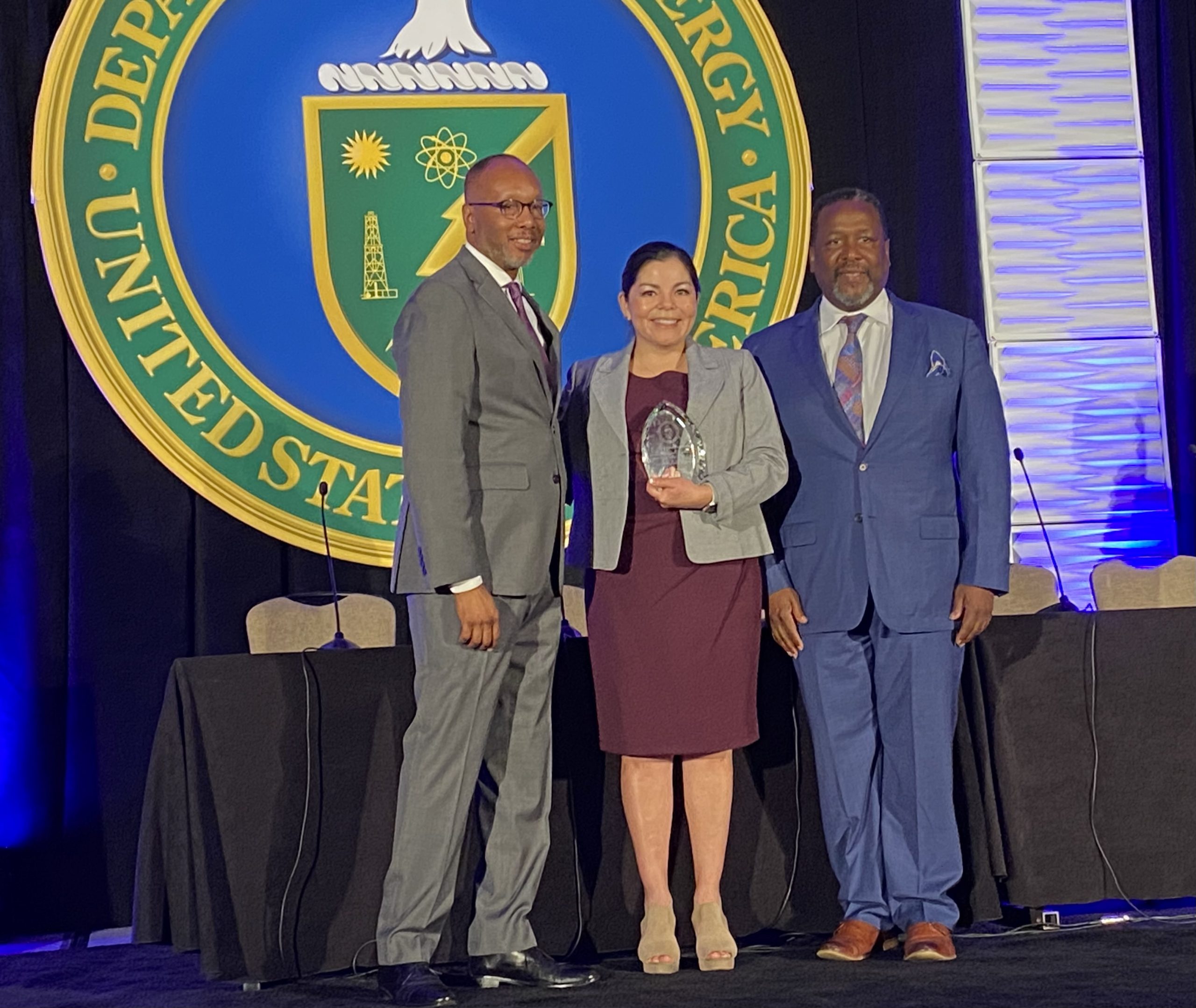 DOE Facility Management Contracting Officer of the Year Sofia Delgadillo-Marrufo, center, a supply chain subcontract manager at Sandia National Laboratories, receiving her award at a ceremony in New Orleans, L.A .on July 11, 2023.