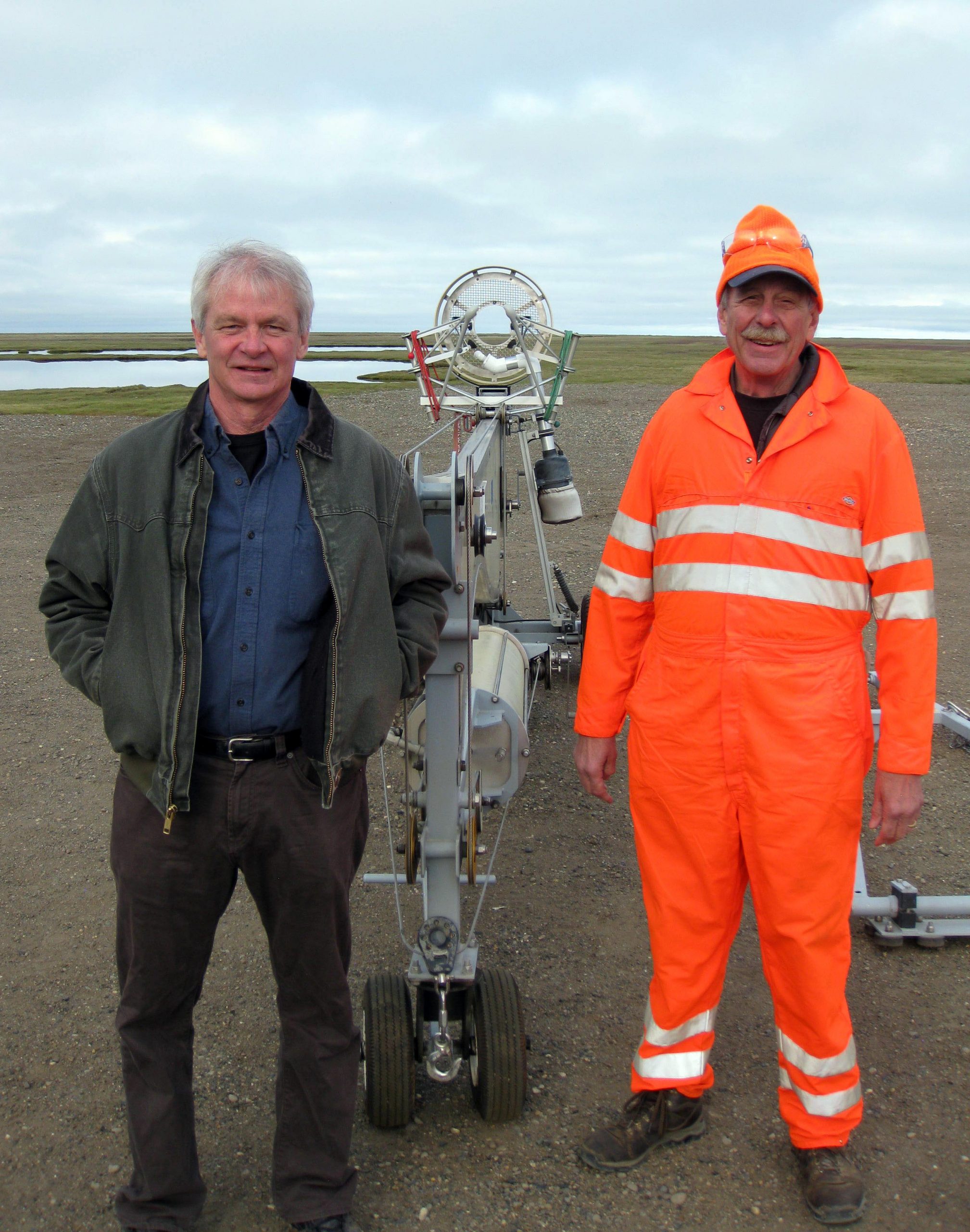 Sandia researcher Mark Ivey, left, and Sandia safety-basis engineer Al Bendure stand next to a folded SkyHook unmanned-aircraft catcher at Oliktok Point. The Arctic tundra stretches out behind them.