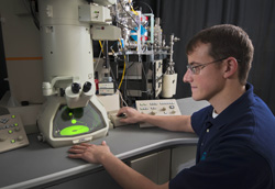 Materials scientist Khalid Hattar sits in front of the in situ ion irradiation TEM. The green light is electrons hitting phosphor.