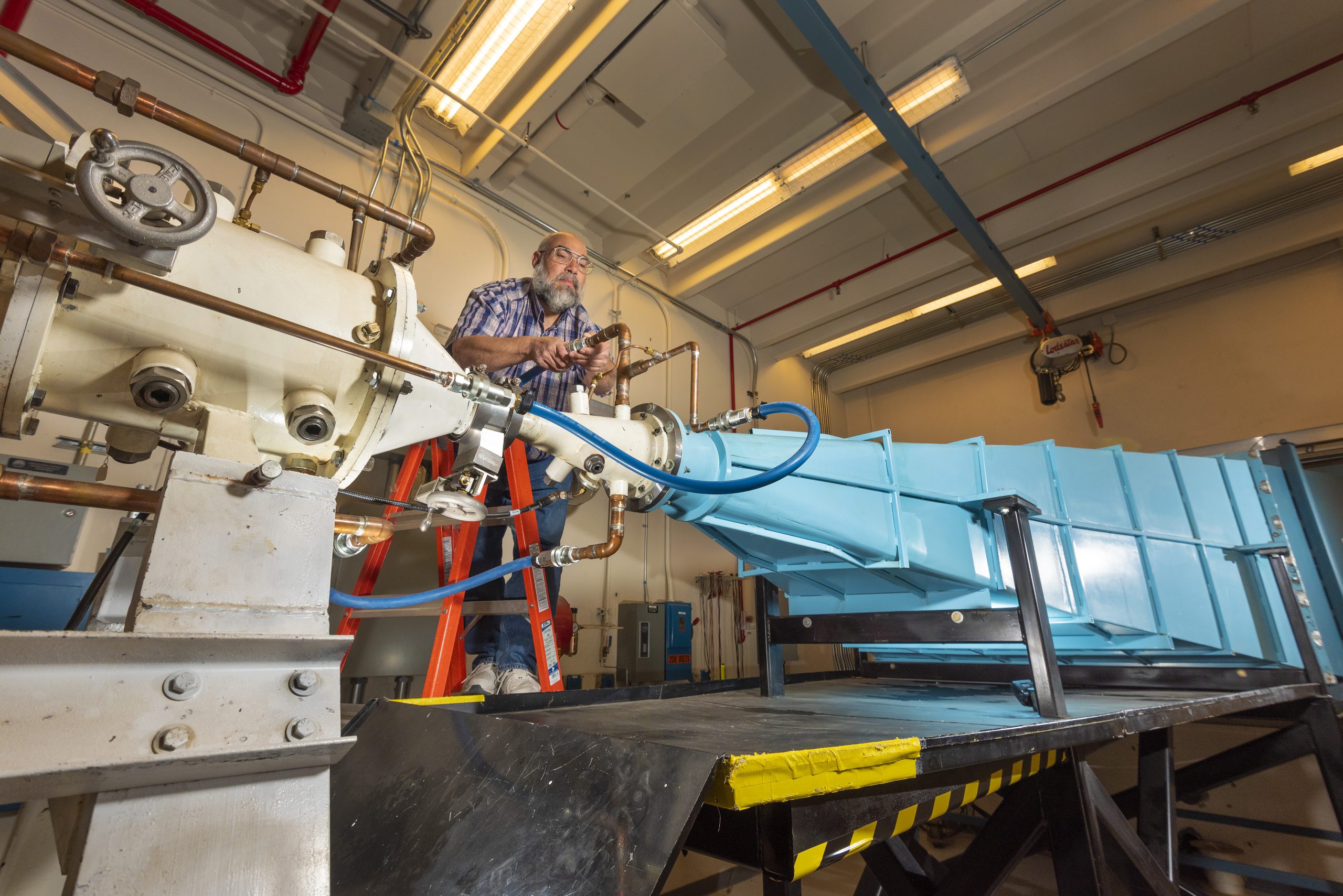 Shocking science!  — At the “friendly” EMP emitter facility called the ElectroMagnetic Environment Simulator, Sandia National Laboratories researcher Leonard Martinez connects a high-voltage-insulating line that circulates oil between a coaxial transmission line