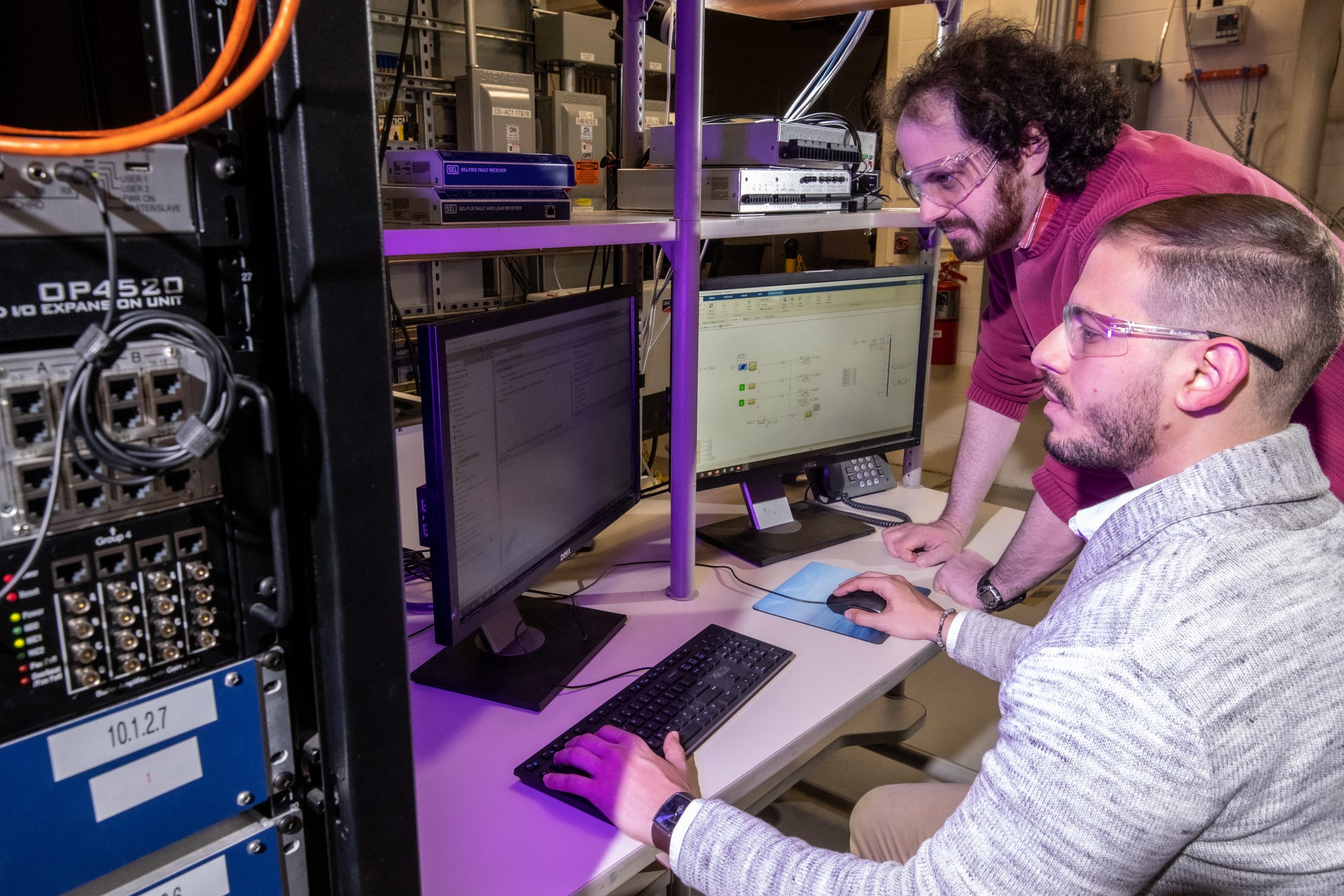 Sandia National Laboratories electrical engineers Rachid Darbali-Zamora, front, and Lee Raskin test out an algorithm on a hardware-in-the-loop set-up at the Distributed Energy Technologies Laboratory.