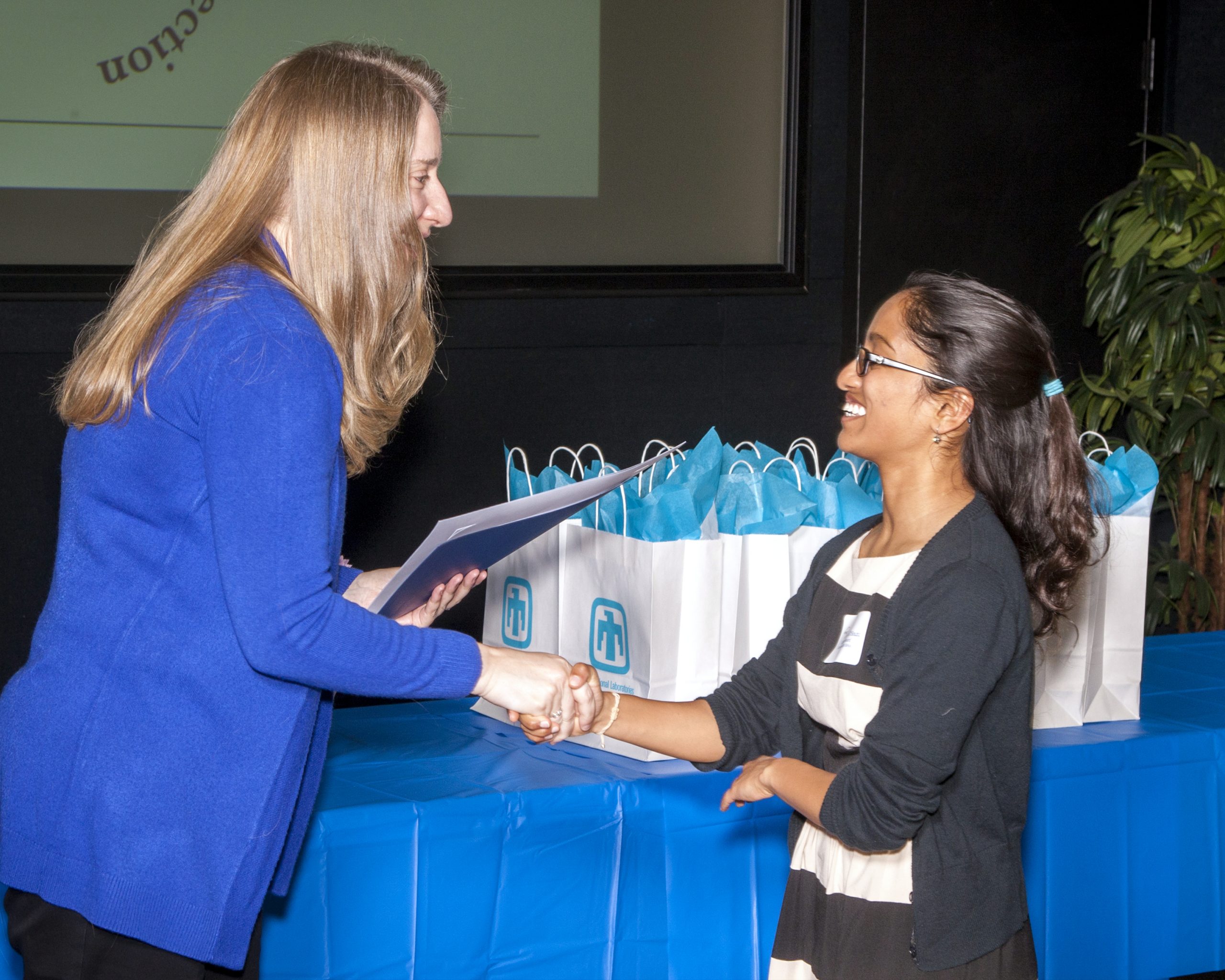Heidi Ammerlahn, left, with the Sandia National Laboratories Women’s Connection and the director of homeland security and defense systems programs, congratulates a student at the 2018 Sandia Math and Science Awards.
