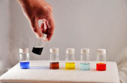 Sandia researchers have discovered a new family of liquid salt electrolytes that could lead to batteries with three times greater energy density than other available storage technologies. The MetILs are, from left to right: copper-based compound, cobalt-based compound, manganese-based compound, iron-based compound, nickel-based compound, and vanadium-based compound.