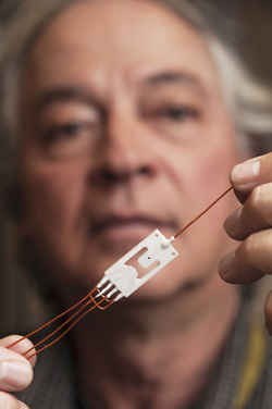 Sandia National Laboratories distinguished technical staff member Juan Elizondo-Decanini holds a prototype of a “neustristor,” a new configuration for neutron generators that turns away from conventional cylindrical tubes in favor of the flat geometry of computer chips. He said the technology is ready to be licensed for some commercial applications, but more complex commercial applications could take five to 10 years. Click on thumbnail for a high-resolution image.