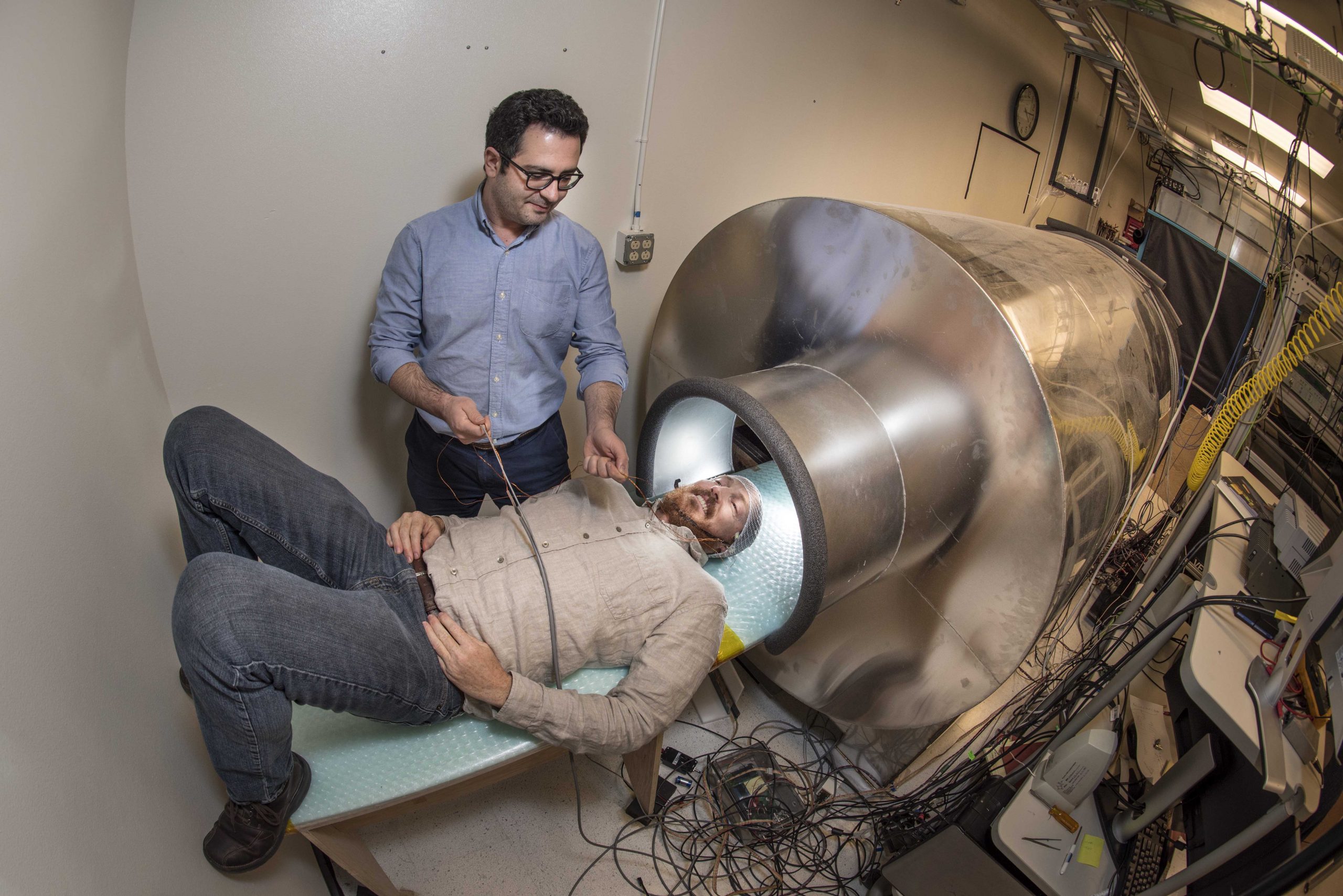 Sandia National Laboratories postdoctoral appointee Amir Borna, left, aids principal investigator Peter Schwindt in entering a person-size magnetic shield in preparation for a magnetoencephalography measurement with their optically pumped magnetometer array.