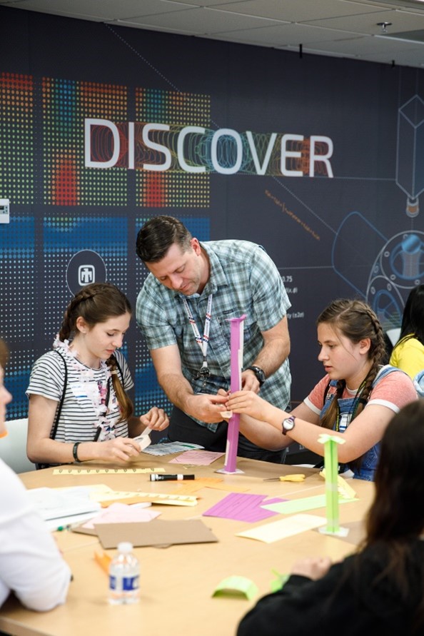 A family works together to build a paper roller coaster during Kids Day at Sandia National Laboratories' California site.