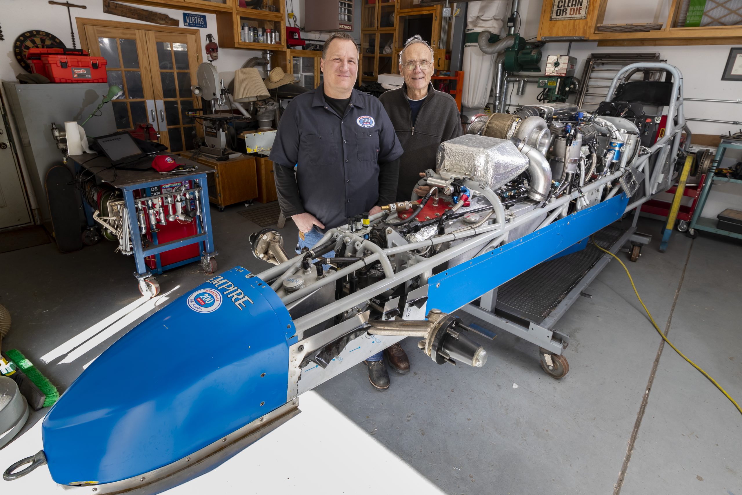 Sandia National Laboratories' Joel Wirth, left, and his father and labs retiree Jack Wirth stand next to their dismantled roadster in Joel Wirth's home garage. Between racing seasons, the car undergoes extensive repairs.