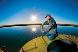 Principal Technologist Richard Simpson adjusts an igniter assembly at a lake Sandia built a few years ago to conduct the world’s largest liquefied natural gas fire tests ever done on water.