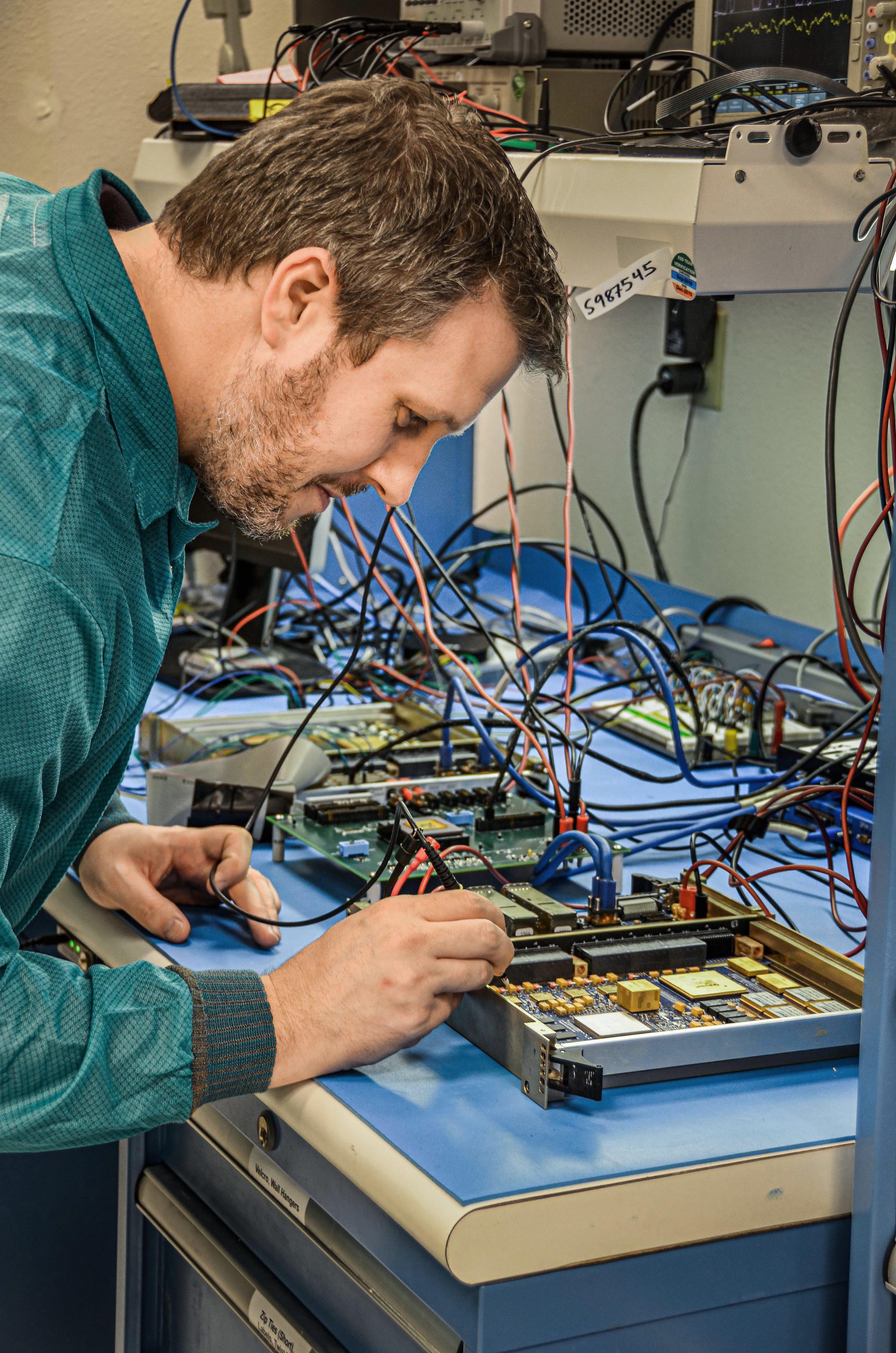 Sandia National Laboratories’ Drew Woodbury works on a flat-sat assembly designed to prove software and cyber defense algorithms work before deploying them on orbiting satellites.