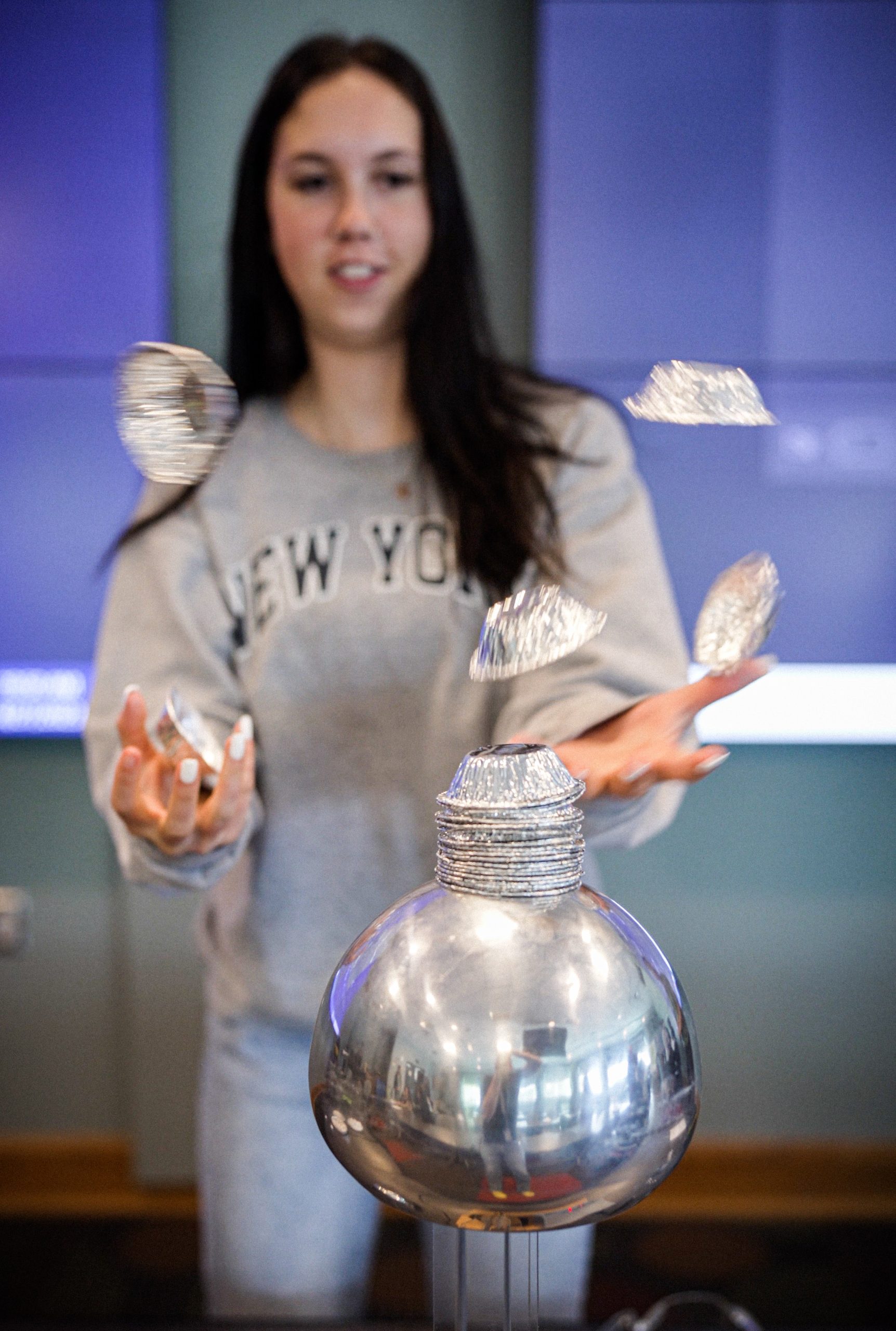 Sophia Hobbs tries to catch foil containers as they fly off of a Van de Graaff generator, demonstrating electrostatic discharge at Kids Day at Sandia National Laboratories.