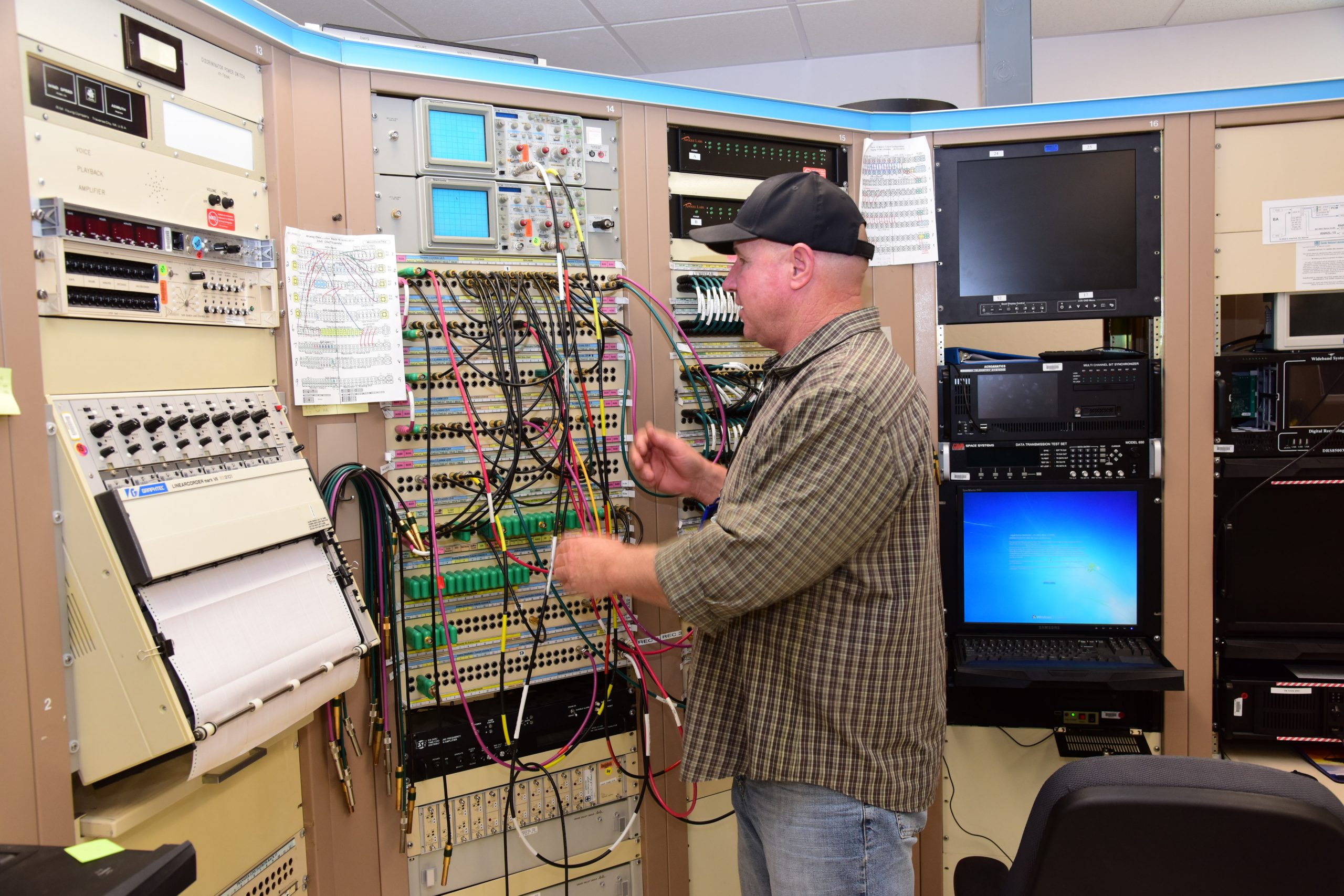 Telemetry systems technologist Mark Skobel adjusts patch cords on a panel in the telemetry ground station at Sandia National Laboratories' Tonopah Test Range. 