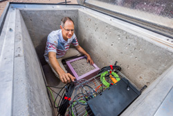 Sandia National Laboratories researcher Tim Draelos inspects a sensor that looks for vibrations in the ground. He worked to develop new software that helps sensors better detect earthquakes and explosions and tune out routine activity such as road traffic and footsteps.