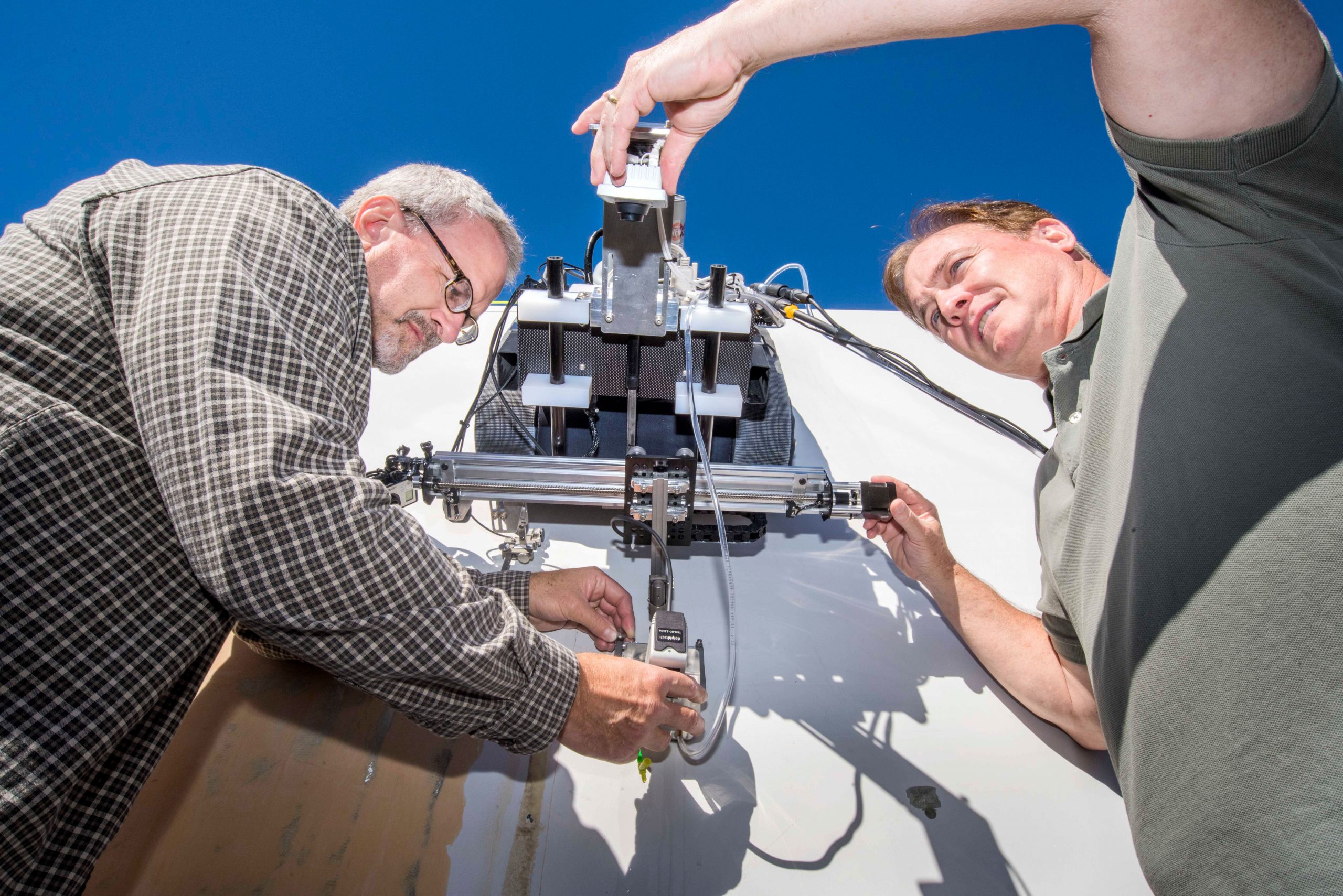 Tom Rice, left, and Dennis Roach of Sandia National Laboratories set up a crawling robot for a test inspection of a wind blade segment.