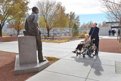 Belva Whitfield and her son Jim share a moment with the likeness of their late husband and father, Willis Whitfield, who is depicted in this bronze statue outside Sandia's MESA complex during a 2012 50th anniversary celebration of the invention of the cleanroom.