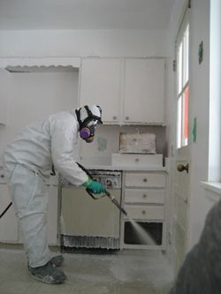 A remediator sprays Crystal Clean on surfaces of a house contaminated with methamphetamine. In an hour, the foam is rinsed clean with water and the remaining liquids are harmless enough to be put down a kitchen drain.