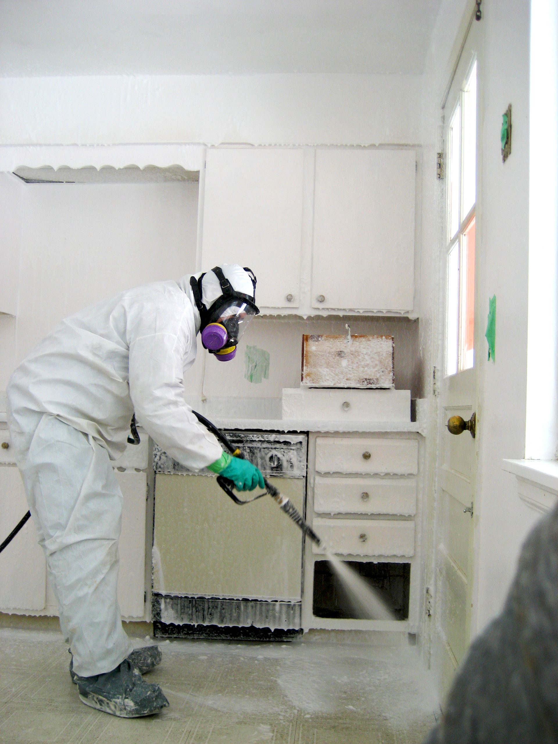 A remediator uses Sandia National Laboratories' decontamination spray on surfaces of a house where methamphetamine was produced. In an hour, the product is rinsed clean with water and the remaining liquids are harmless enough to be put down a kitchen drain.