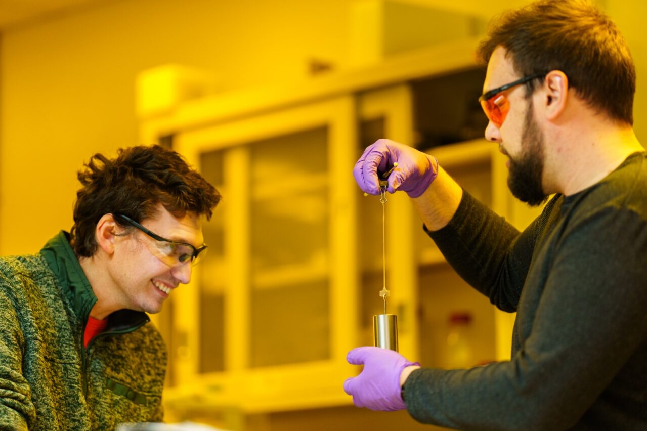 Samuel Leguizamon, left, watches as Alex Commisso stretches 3D material that they printed at Sandia National Laboratories, using Selective Dual-Wavelength Olefin Metathesis 3D-Printing, or SWOMP.