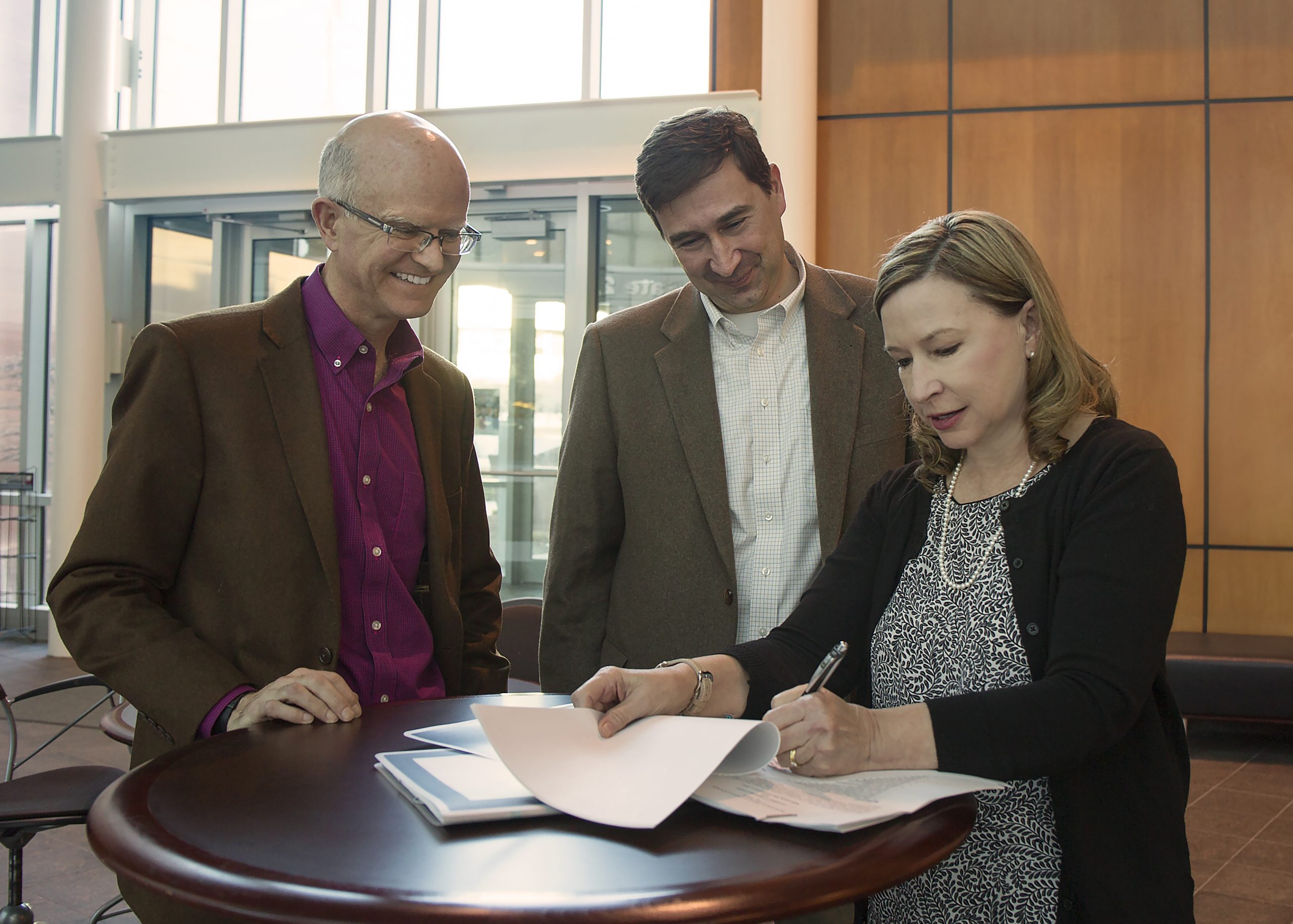 Mary Monson, Sandia National Laboratories Industry Partnerships senior manager, signs a licensing agreement with scientist-turned-entrepreneur Murat Okandan, center, and Sandia Research Strategy and Partnerships Director Andy McIlroy. Okandan left Sandia in 2015 through the Entrepreneurial Separation to Transfer Technology program to commercialize Sandia’s microsystems enabled photovoltaics, also known as solar glitter.