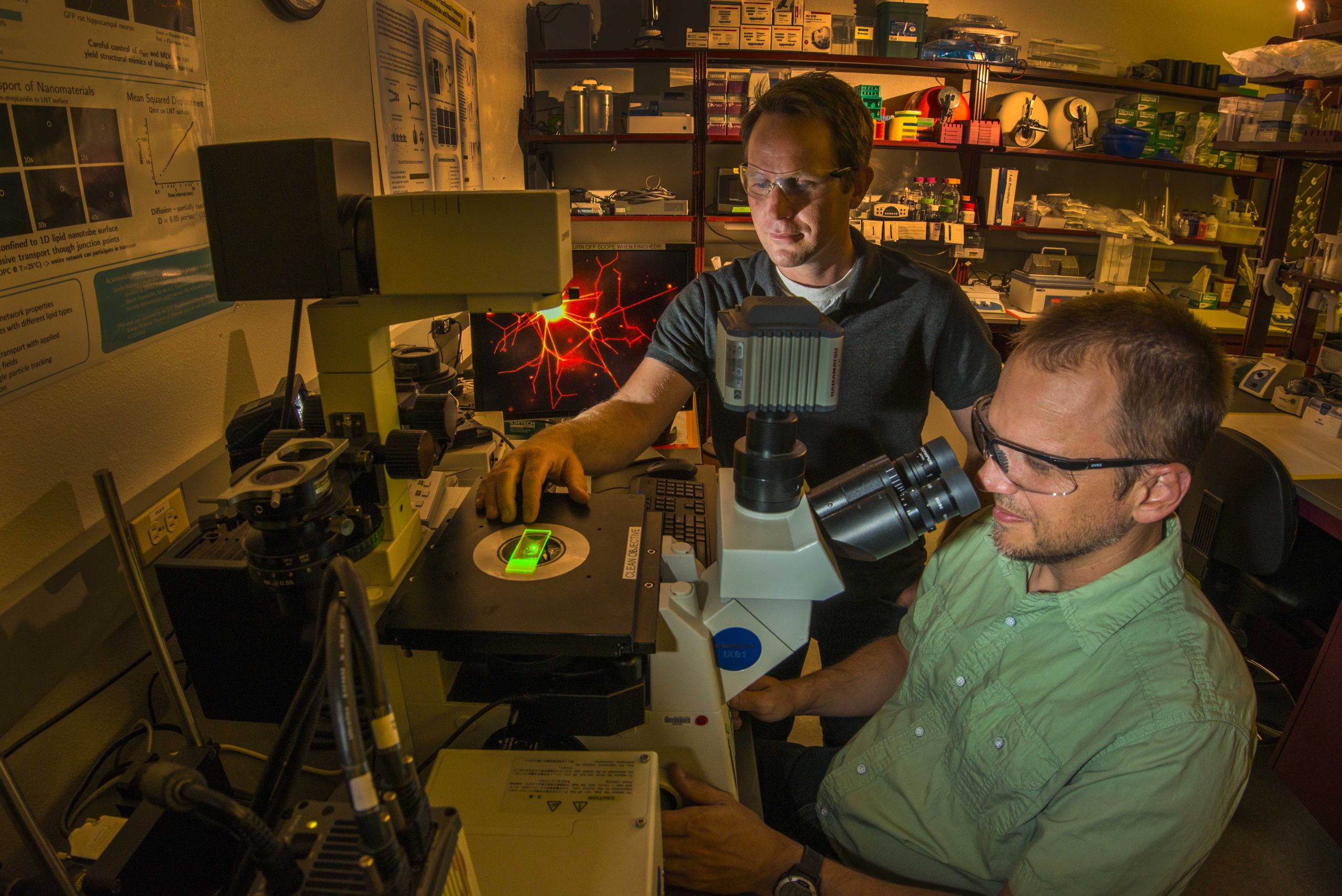 Sandia National Laboratories researchers George Bachand and Wally Paxton at a confocal microscope illuminating the first biomolecular machines to assemble complex polymer structures.