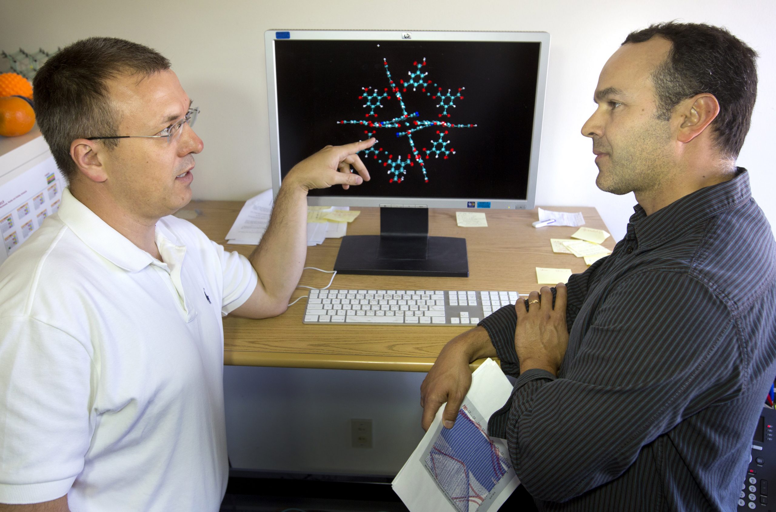Vitalie Stavila, left, and Catalin Spataru  discuss modeling approaches to conduct electronic structure calculations. The TCNQ molecule changes the MOF’s properties to enable thermoelectric conductivity.