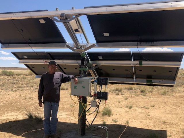 Rancher Delbert Shirley stands beside the Remote Well Solutions LIZER2P solar pumping plant installed on his ranch on the Navajo Nation, a project made possible by the New Mexico Small Business Assistance Program, Sandia National Laboratories and others.