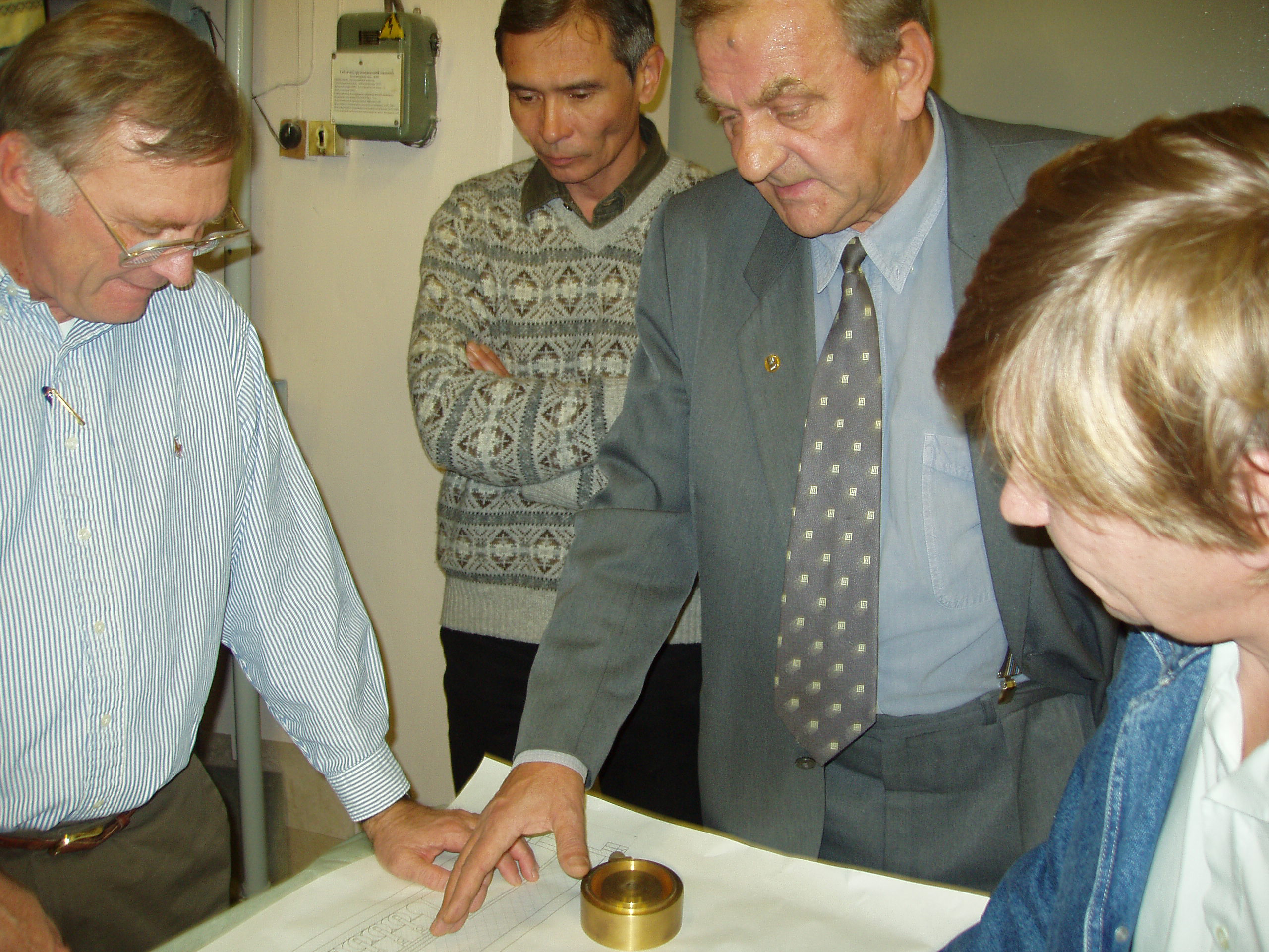 Boris Kovalchuk (HCEI, in gray suit) demonstrates design of a new LTD system to Sandian Dillion McDaniel as Alexandar Kim looks on. (Far right, unknown person.)