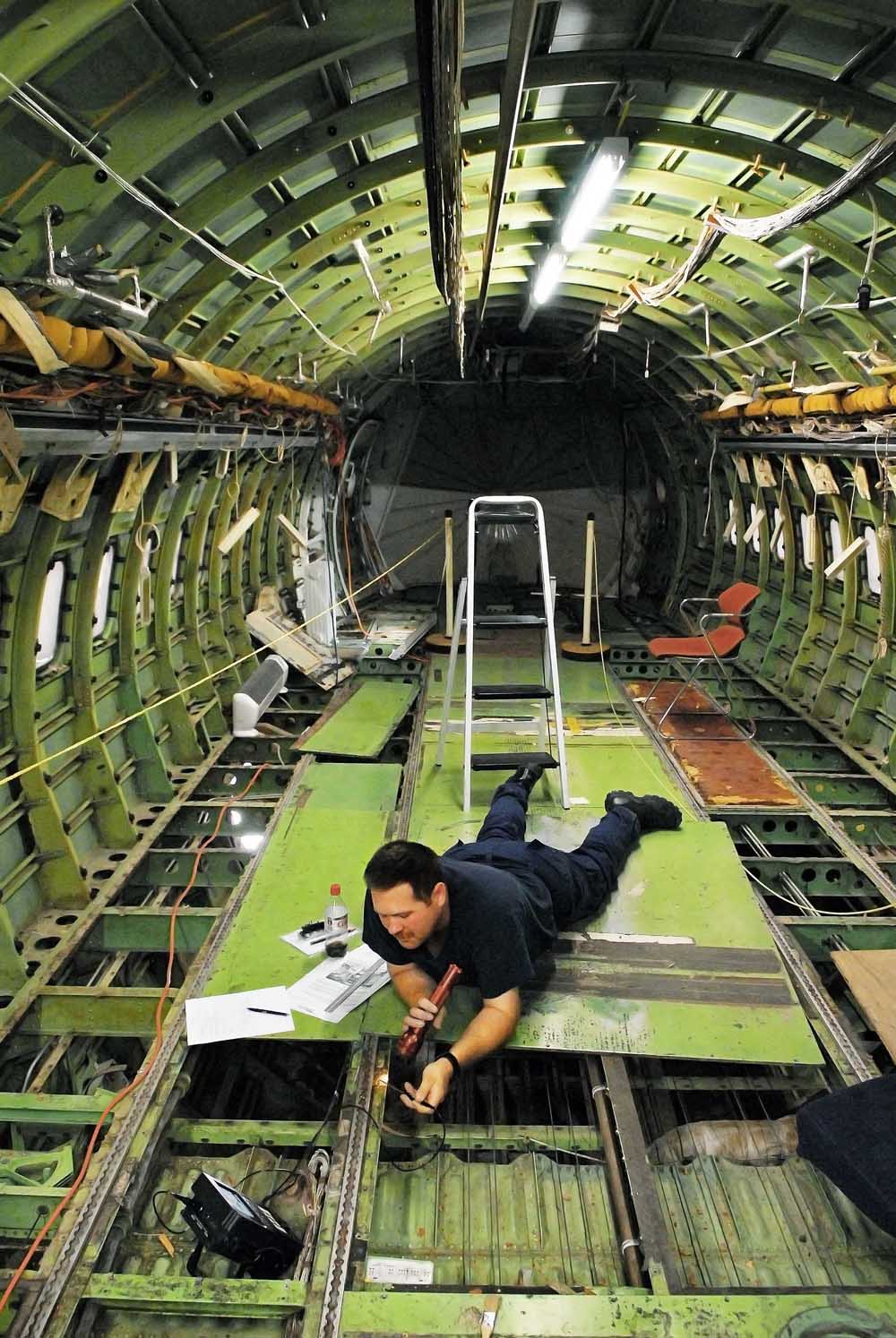 Adam Hoke, an aviation maintenance technician with the U.S. Coast Guard, inspects the belly of a Boeing 737 using an eddy current scanner. (Photo by Randy Montoya)
