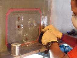 A Sandia researcher incorporates sensors that monitor stress into a Sandia-installed composite repair in a structural beam of a highway overpass.
