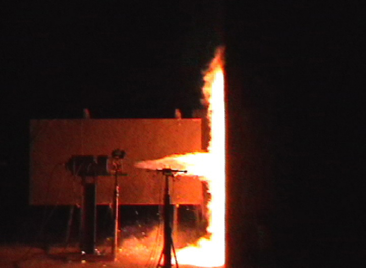 The experiment shown in these two images helps Sandia scientists understand the hazards associated with an unintended release of hydrogen. Both images show the flames that emerge after a high-pressure jet of hydrogen is released toward a wall made of cinder block. The radiated heat flux emanating from the flames, when analyzed and measured, helps researchers evaluate the effectiveness of a barrier wall in mitigating the risks of hydrogen releases in a dispensing station setting. The image on top was taken with an infrared-sensitive camera, which allows researchers to conduct tests during daylight hours.