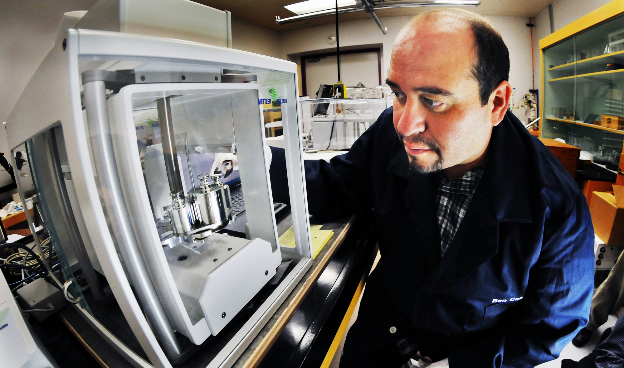 Ben Casados, Sandia technologist, looks at kilogram samples in a mass comparator. (Photo by Randy Montoya)<br />
Download 300dpi 1.6MB JPEG image (Media are welcome to download/publish this image with related news stories.)