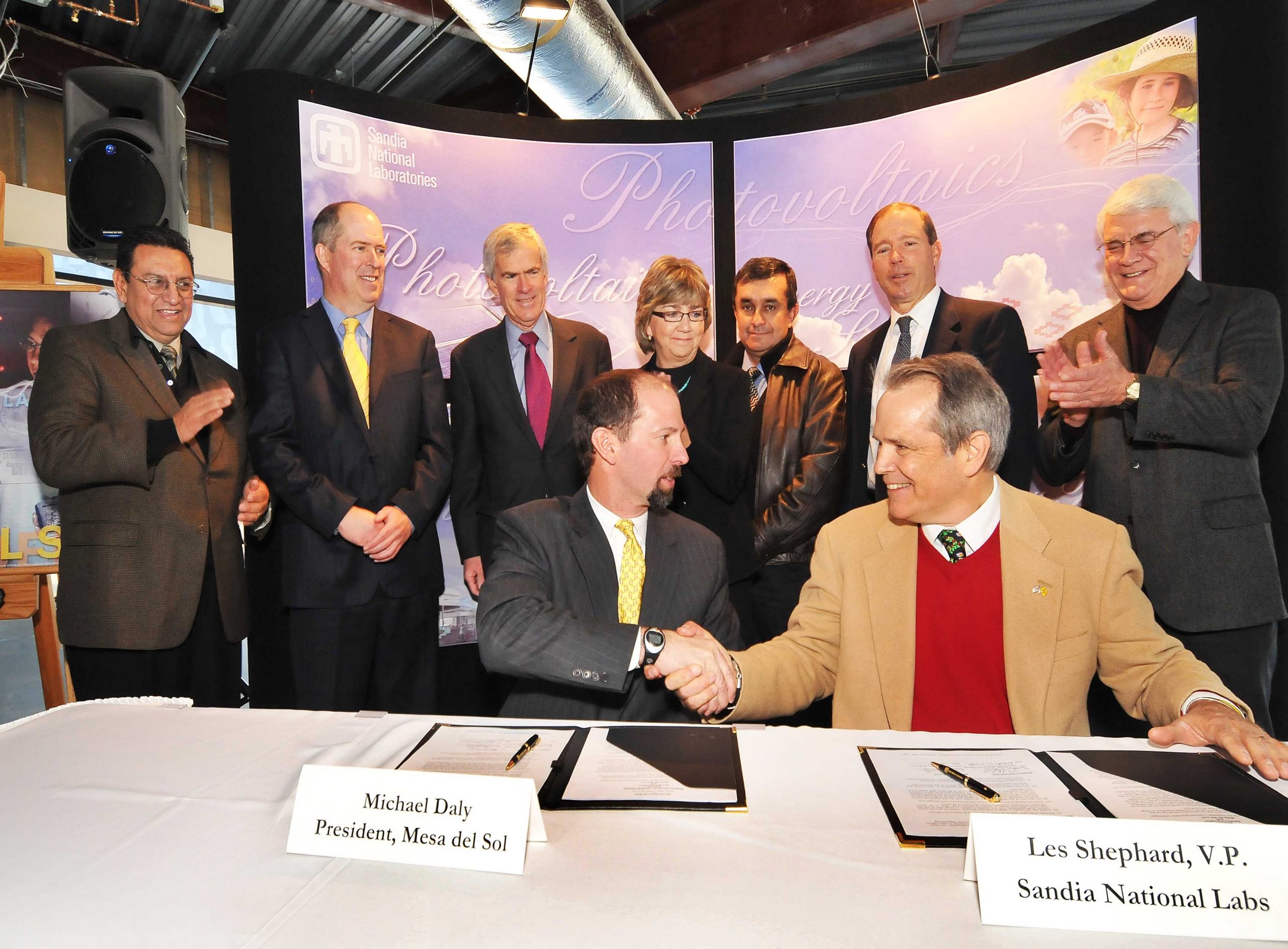 Michael Daly, president of Mesa del Sol, and Les Shephard, Sandia's vice president for Energy, Security, and Defense Technologies, shake hands following the signing of the agreement between Sandia and Mesa de Sol.<br />
<br />
Behind them (from left to right) are Lenny Martinez, policy advisor for the New Mexico Science and Technology Office; Peter Mitchell, economic development director, City of Albuquerque; U.S. Senator Jeff Bingaman, (D-NM); Lt. Gov. Diane Denish; Dennis Garcia, assistant commissioner New Mexico State Land Office; Rep. Tom Udall (D-NM); and Fred Mondragon, New Mexico economic development secretary. (Photo by Randy Montoya)<br />
Download 300dpi 500 KB JPEG image (Media are welcome to download/publish this image with related news stories.)