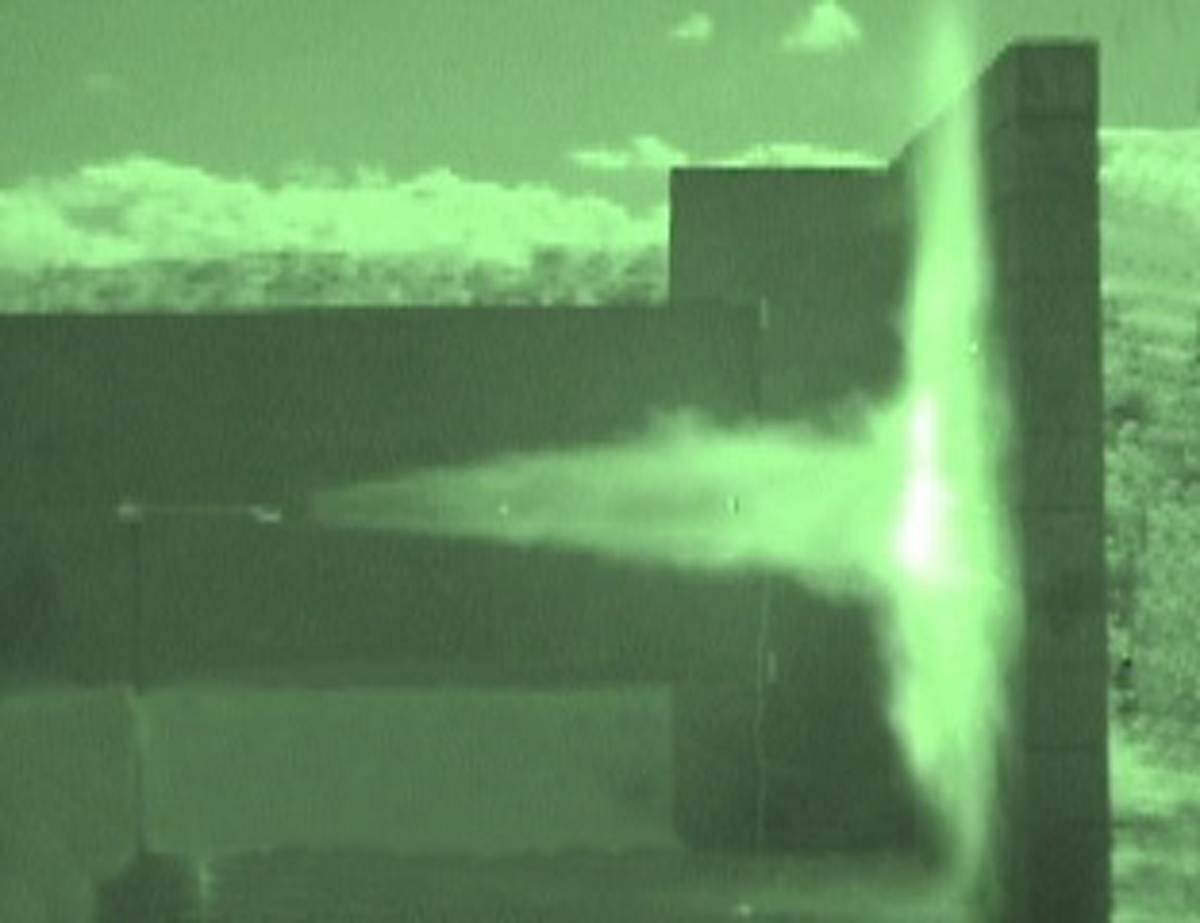 The experiment shown in these two images helps Sandia scientists understand the hazards associated with an unintended release of hydrogen. Both images show the flames that emerge after a high-pressure jet of hydrogen is released toward a wall made of cinder block. The radiated heat flux emanating from the flames, when analyzed and measured, helps researchers evaluate the effectiveness of a barrier wall in mitigating the risks of hydrogen releases in a dispensing station setting. The image on top was taken with an infrared-sensitive camera, which allows researchers to conduct tests during daylight hours.