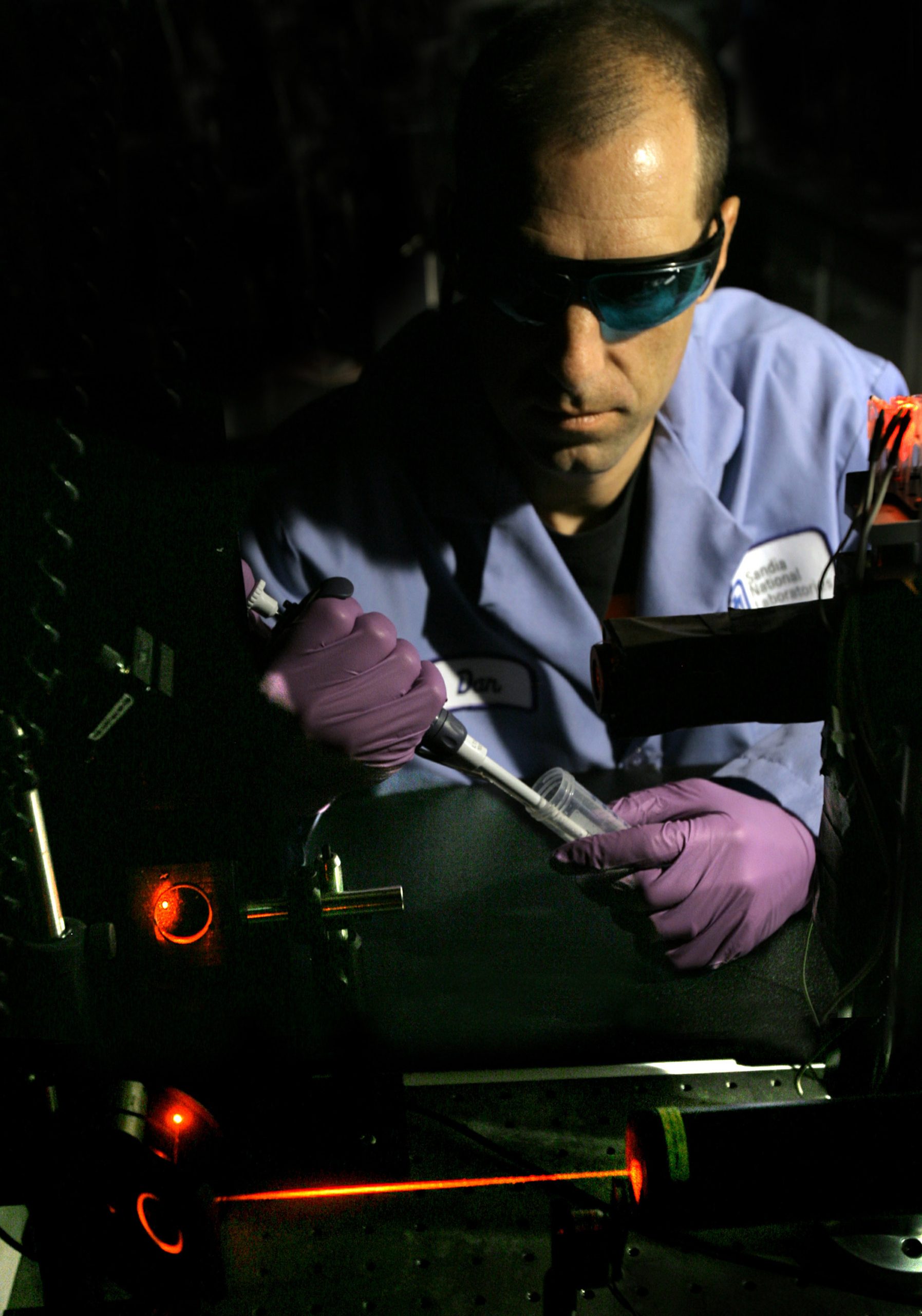 Sandia biochemist Dan Throckmorton prepares to add a sample to the prototype diagnostic device.  After Dan adds the sample, computer-controlled electronics direct a series of sample analysis steps.  Laser-induced fluorescence is used for highly sensitive detection of assay products. The final diagnostic device will feature a miniaturized, portable fluorescence detector.