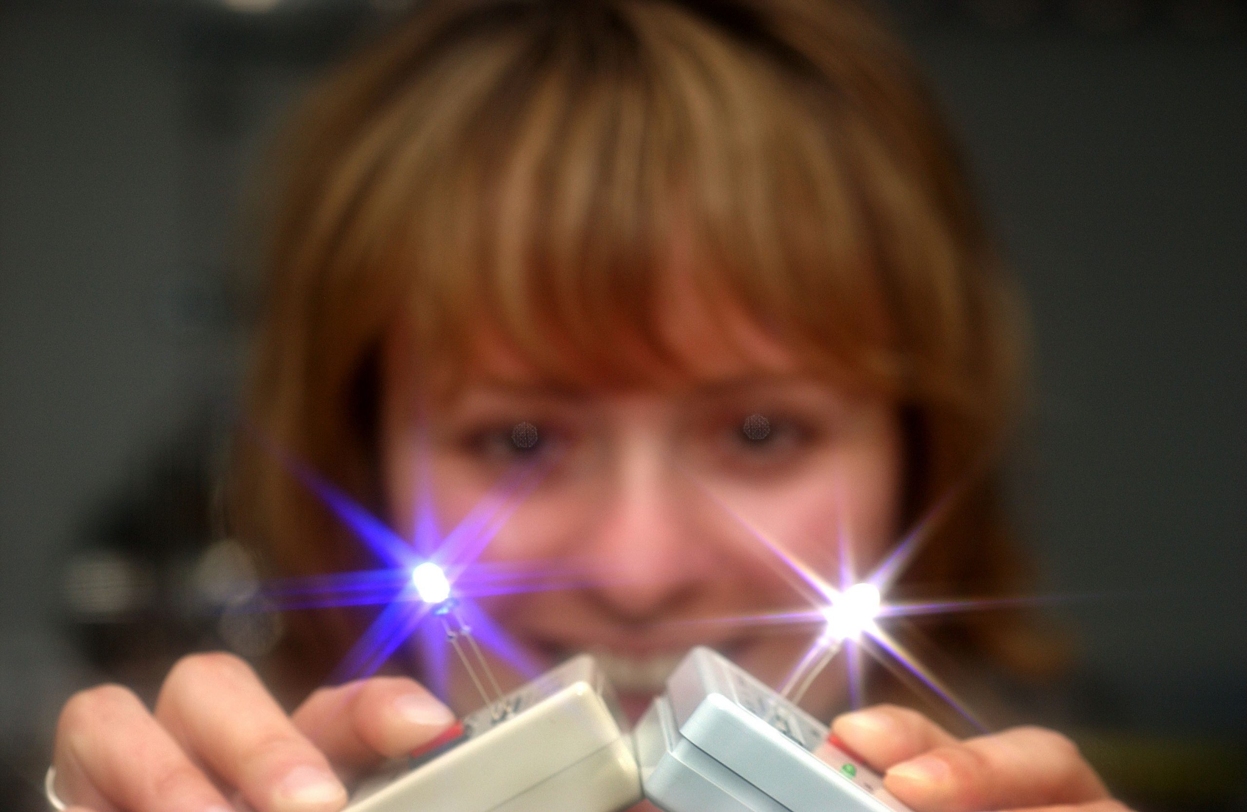 LAUREN ROHWER displays the two solid-state light-emitting devices using quantum dots her team has developed. One is blue and the other is white. (Photo by Randy Montoya)